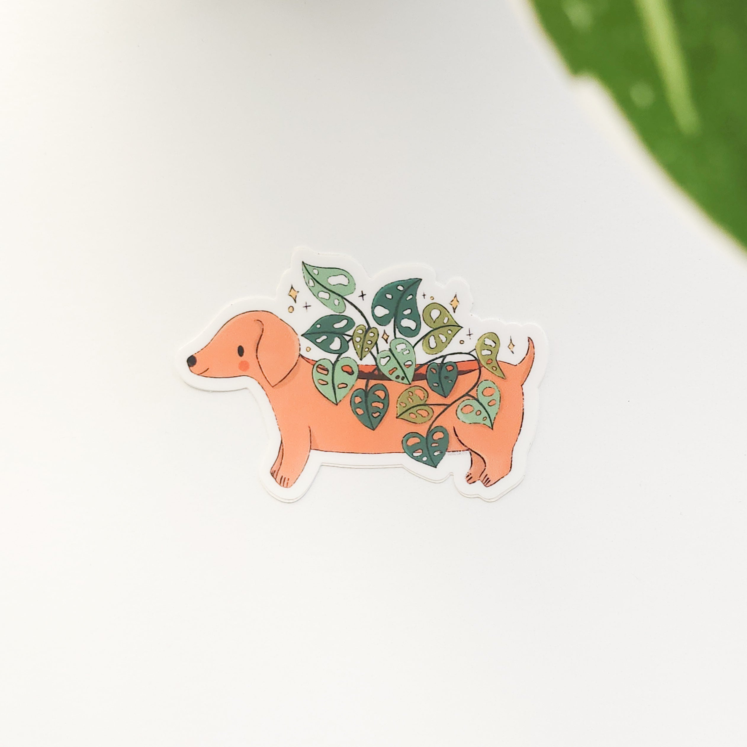 illustrated sticker of a dachshund planter on a white background with a leaf