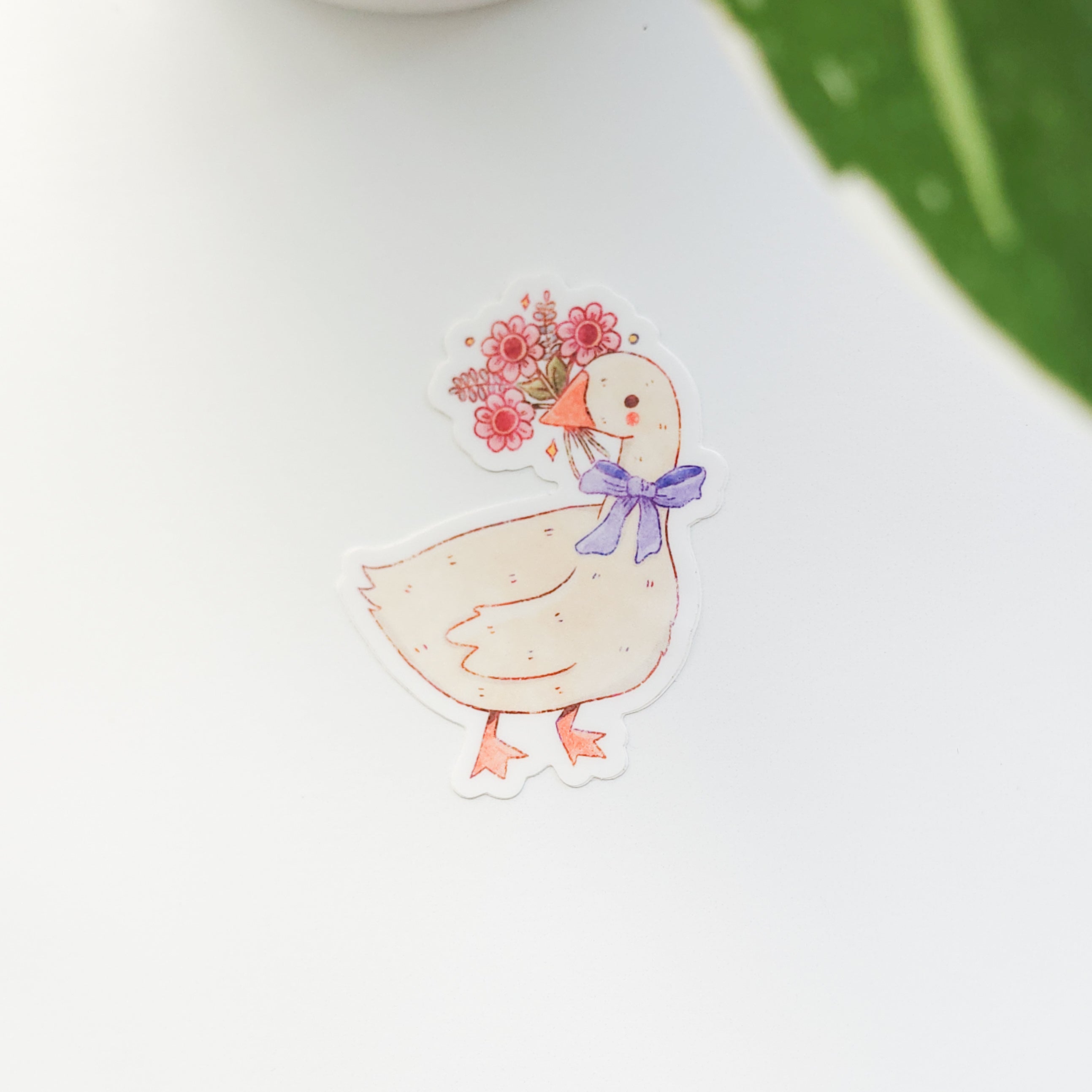 sticker of a goose holding a bouquet of flowers on a white background with a leaf