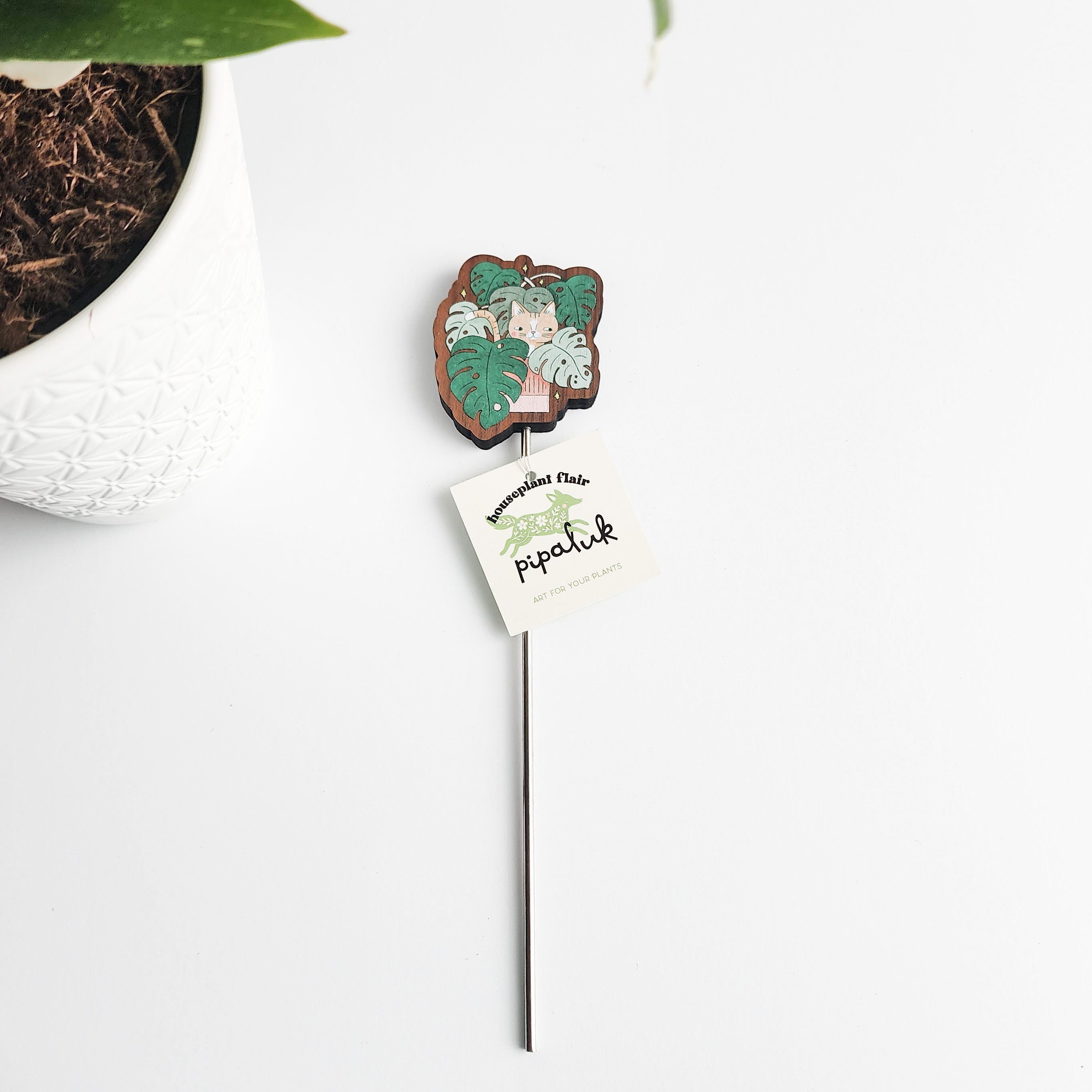 Wooden cat plant pick with a pipaluk label on a white background