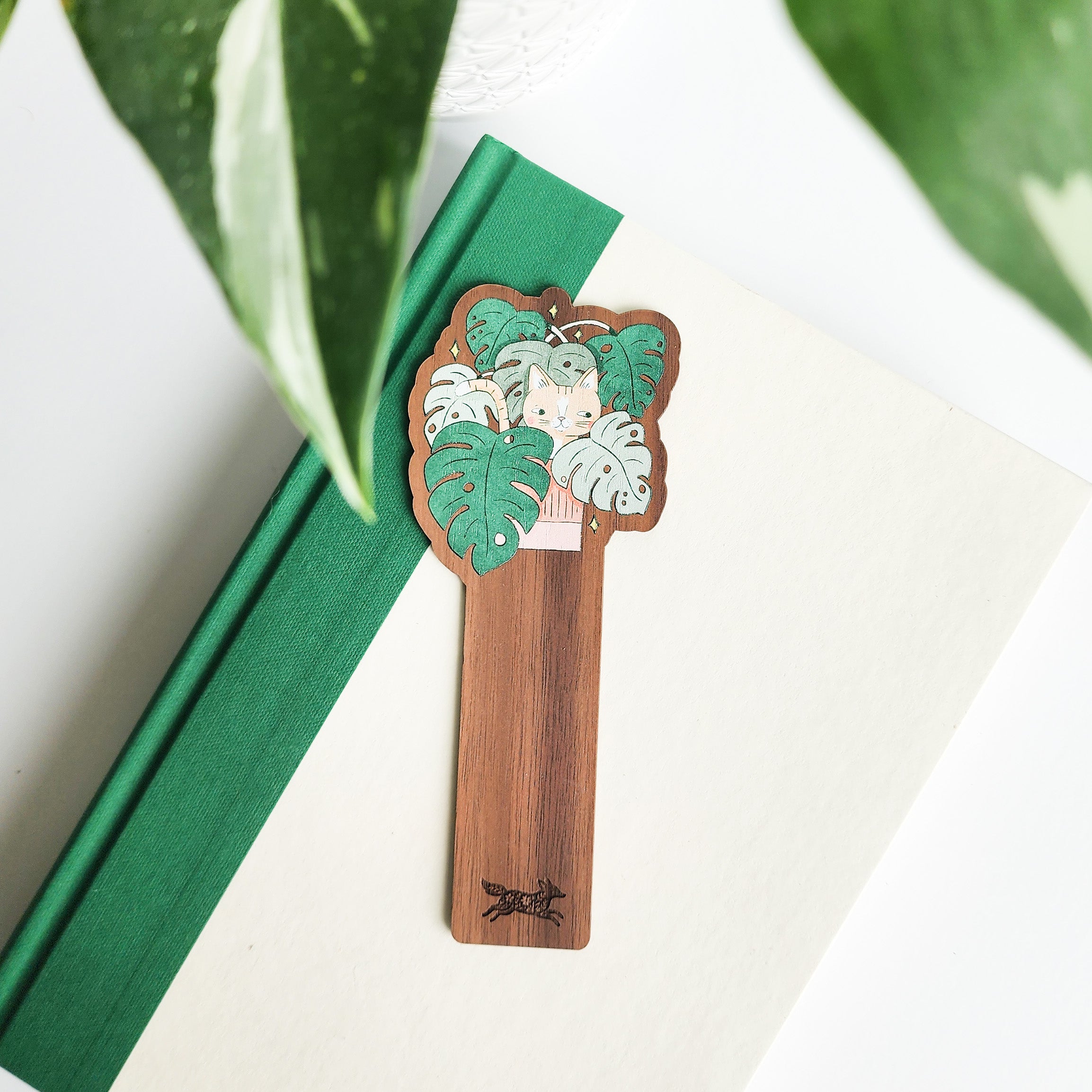 cat bookmark sitting on a green and white book on a white background