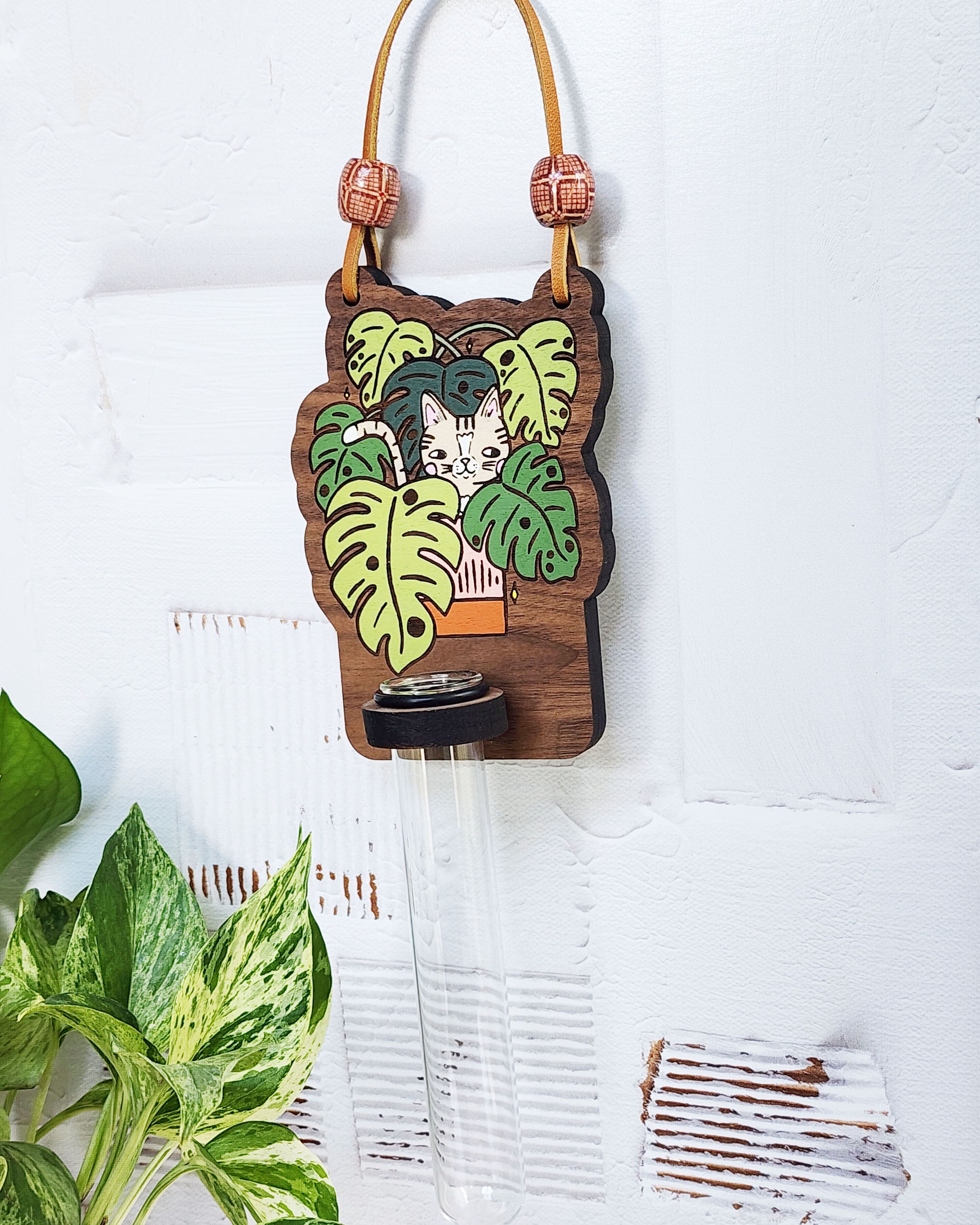 propagation station with a cat in a plant painted on it hanging on white wall
