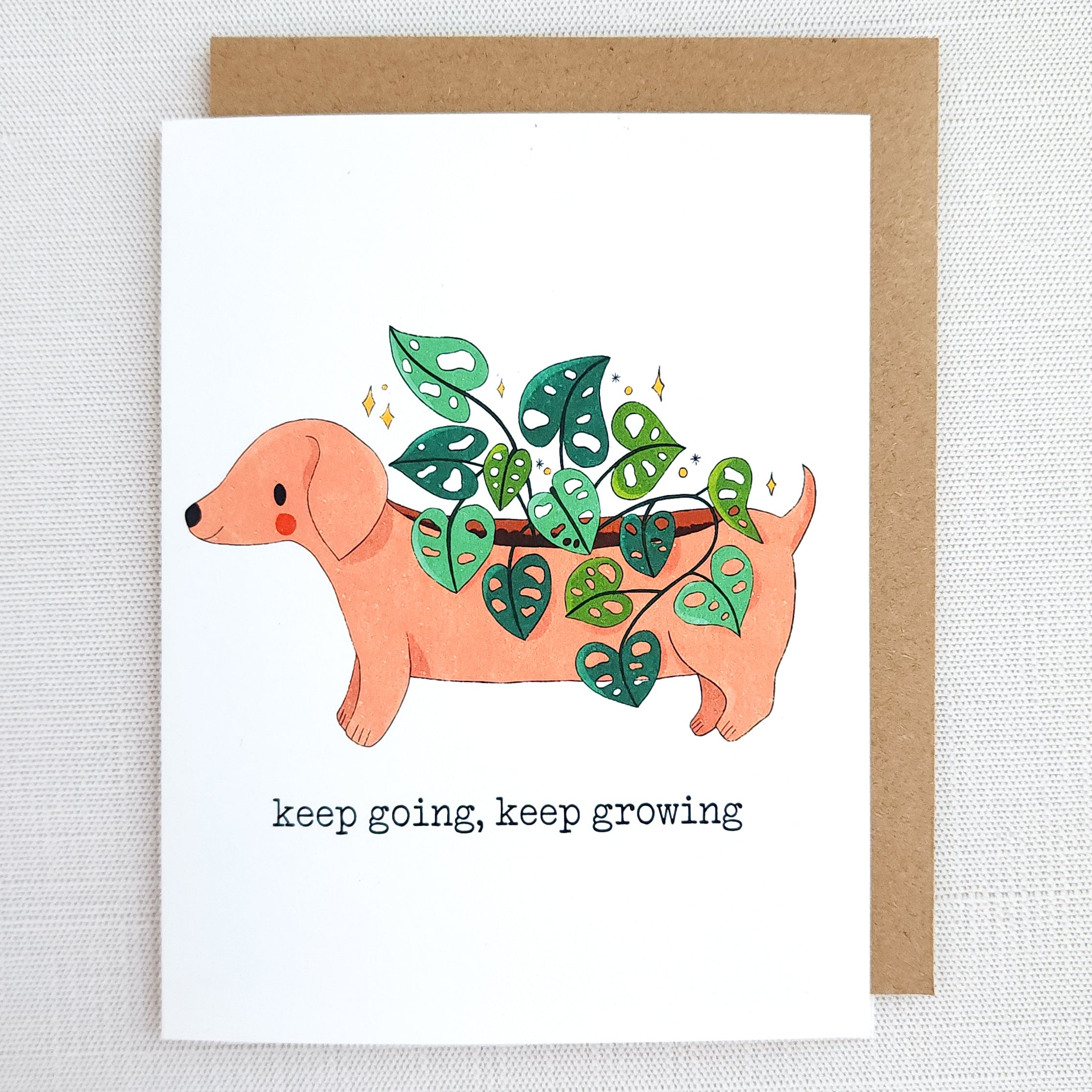 Card with a dachshund illustration holding a plant, text &