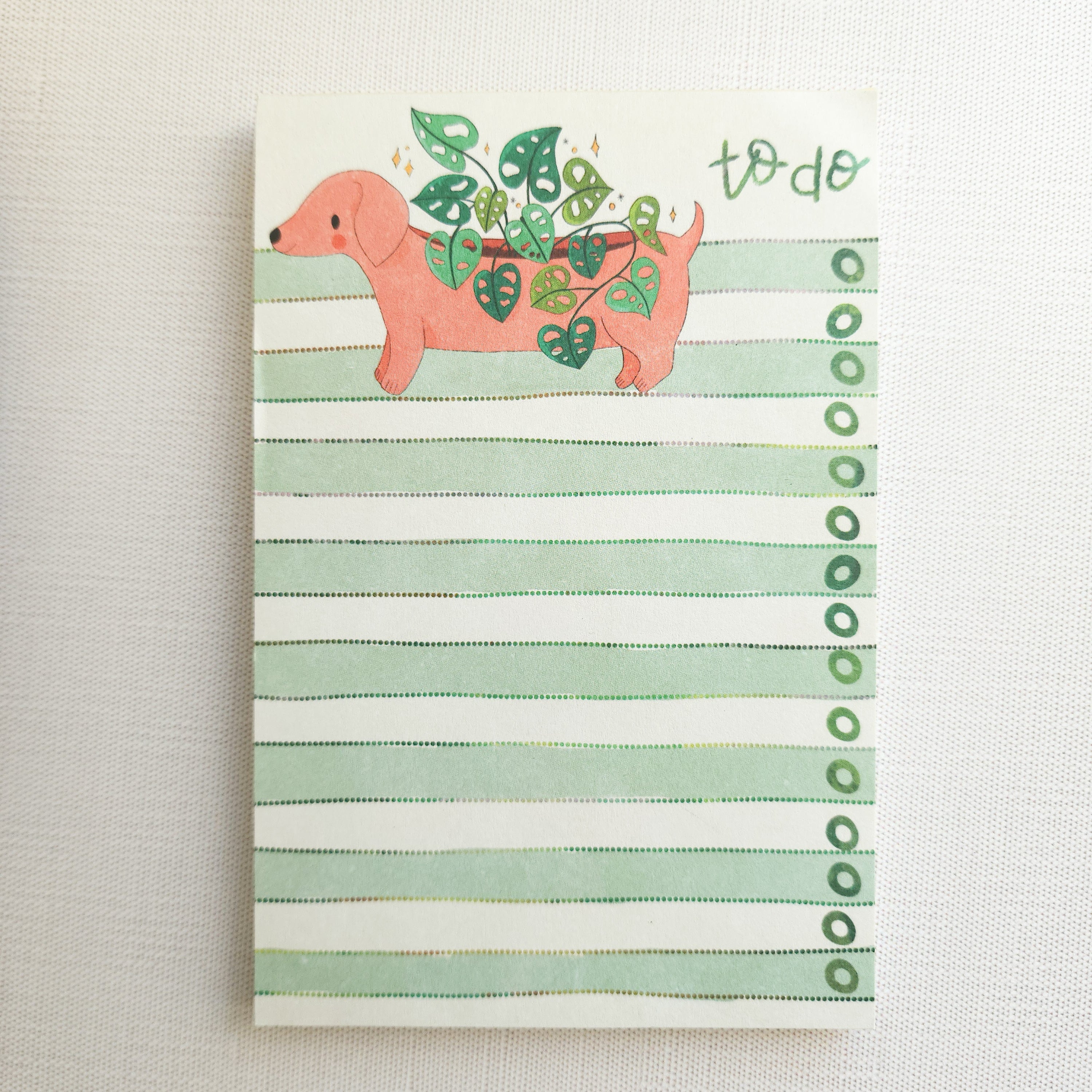 notepad with a dachshund illustration and green stripes on a neutral background