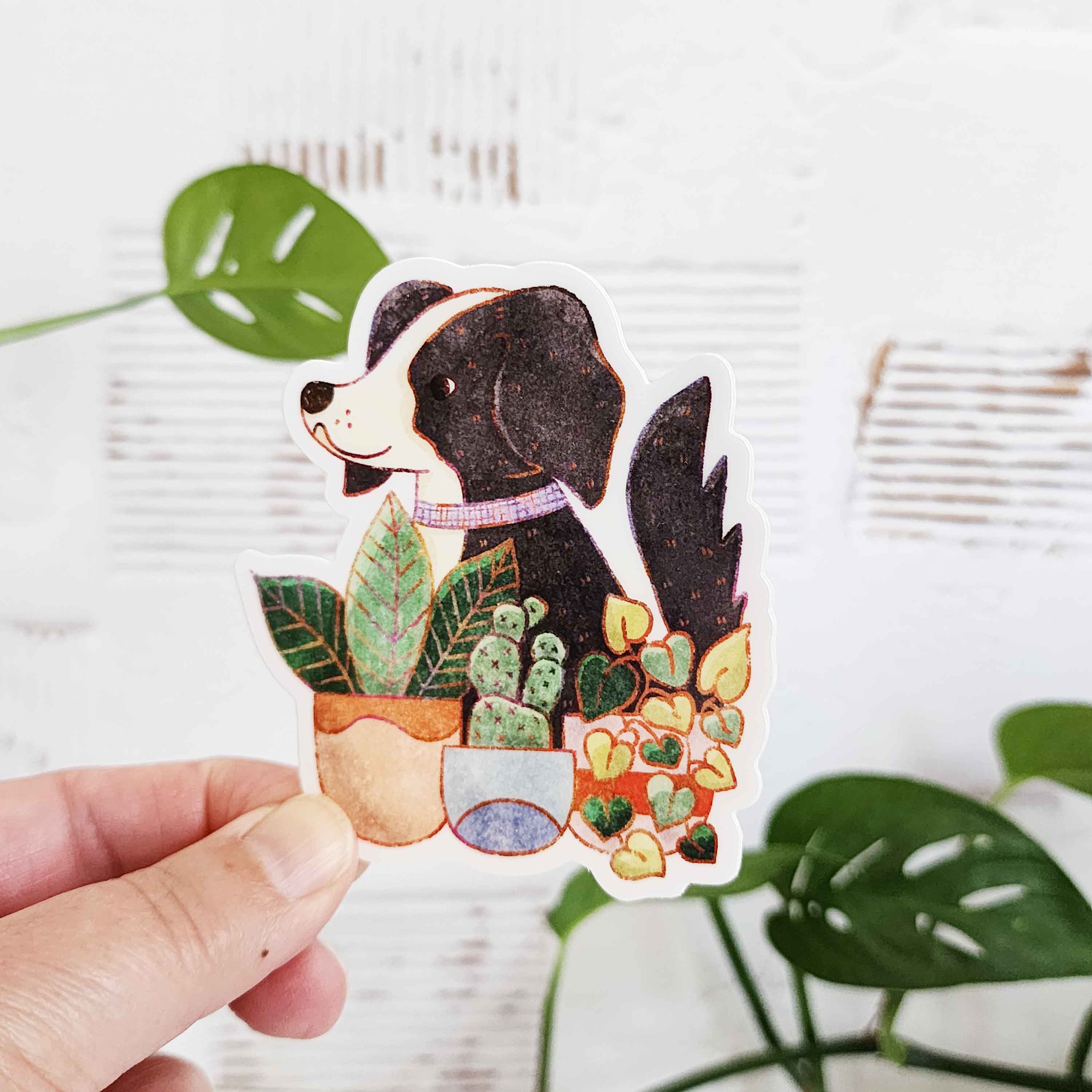 sticker of a black and white dog sitting in front of potted plants