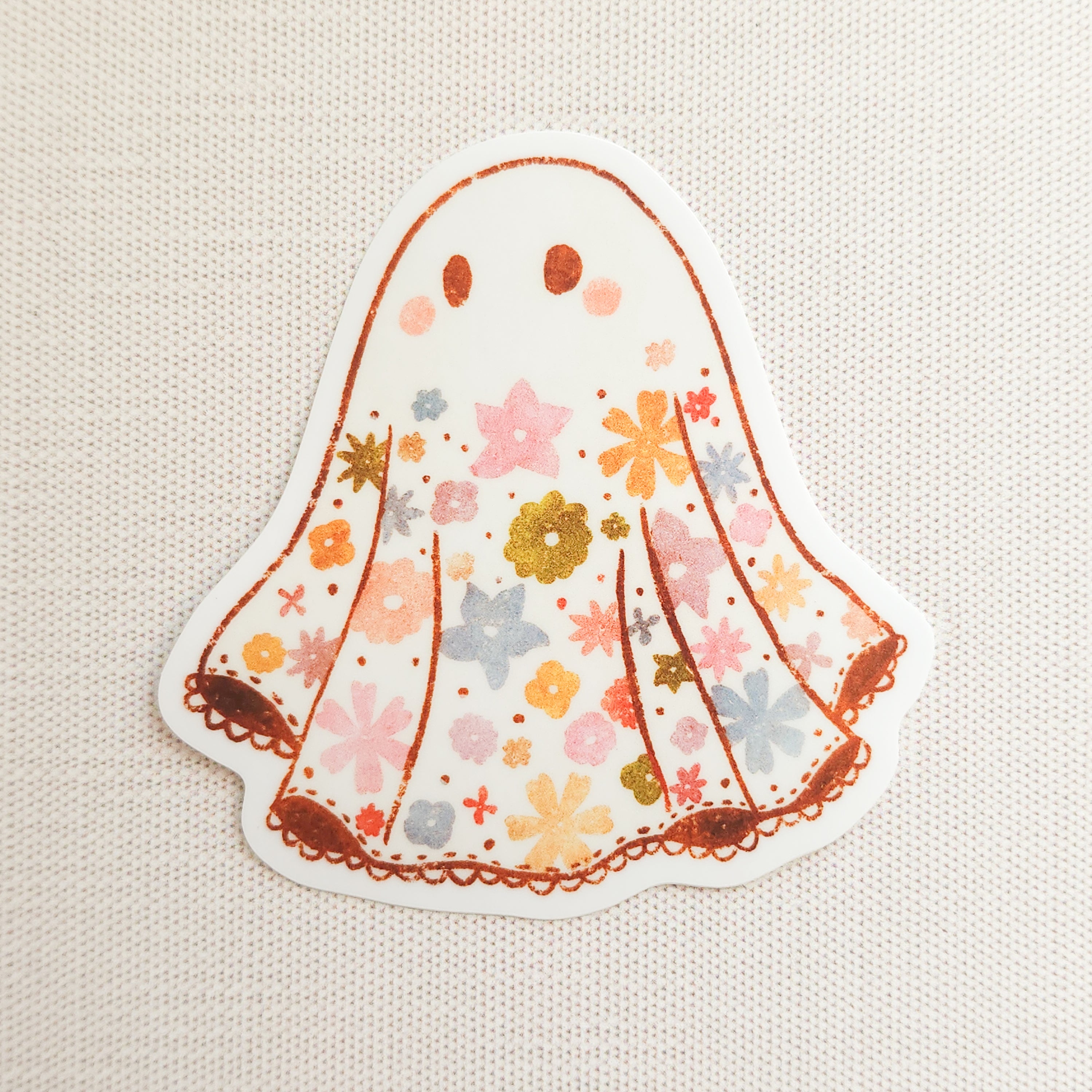 sticker with an illustrated ghost with a floral design on a linen background