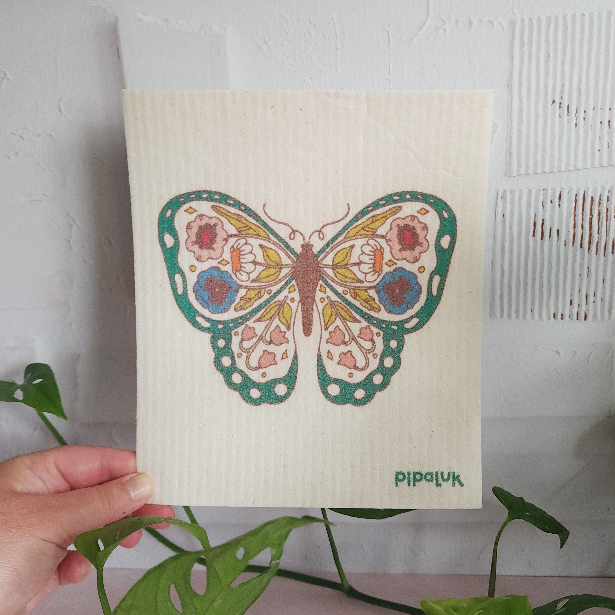 floral butterfly dishcloth held in a hand against a white background