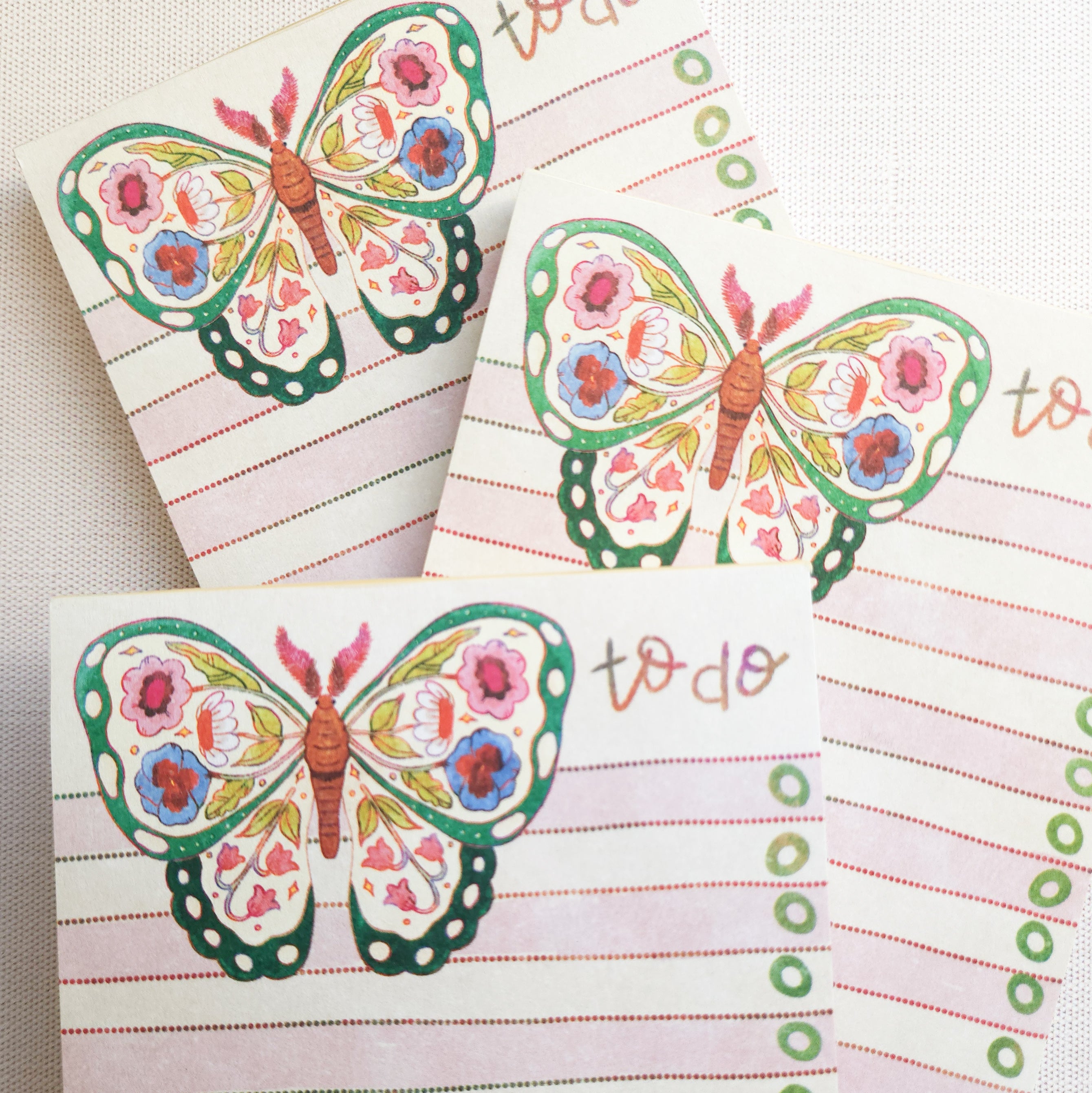 3 floral butterfly notepads stack on each other on a neutral background