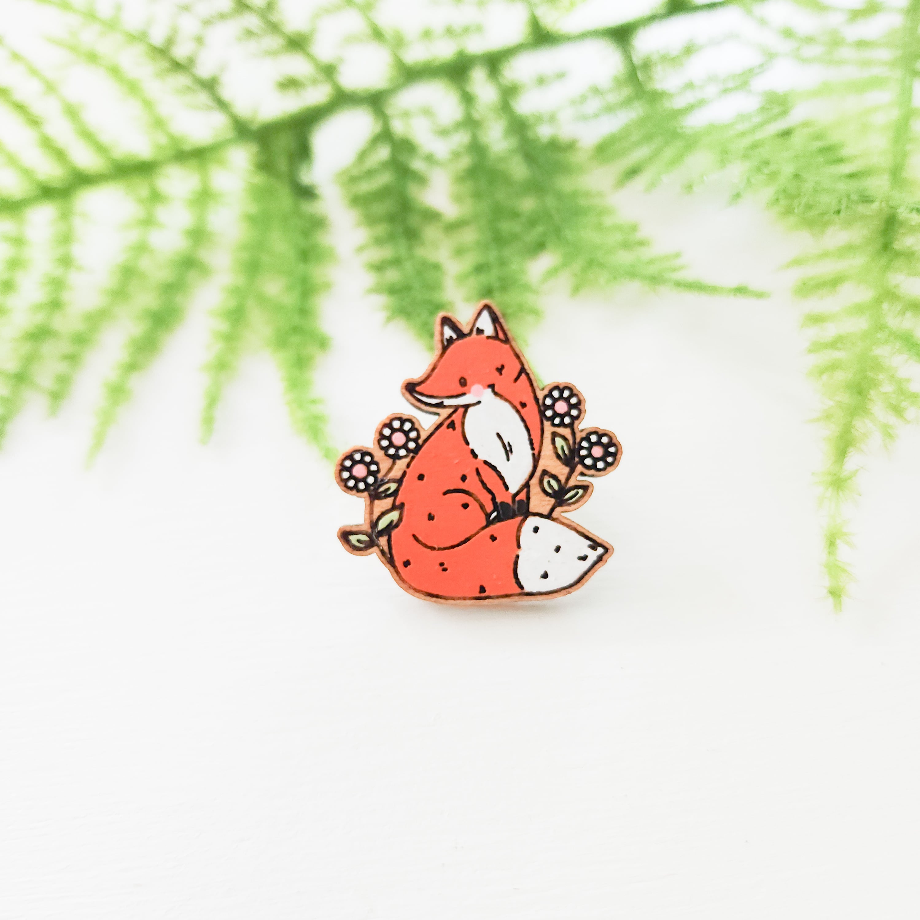 orange fox with pink cheeks surrounded by daisies