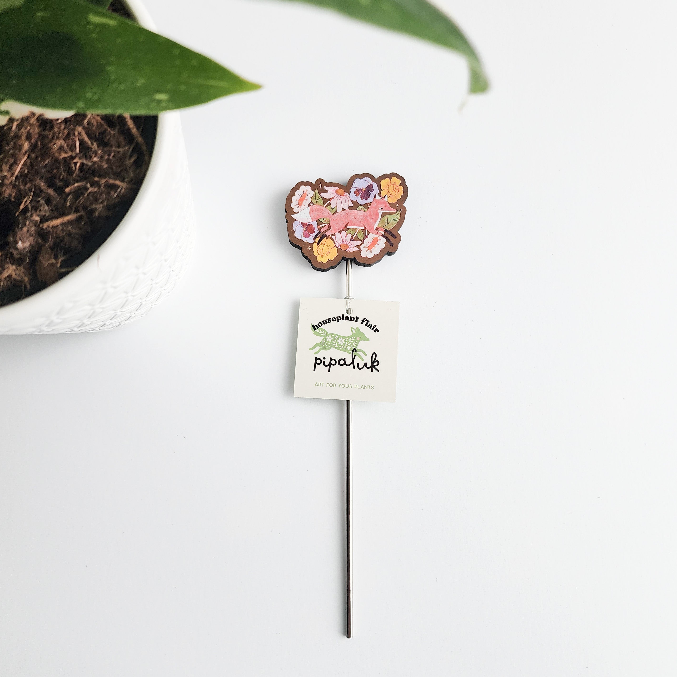 floral fox plant pick with pipaluk label with a pot in the background