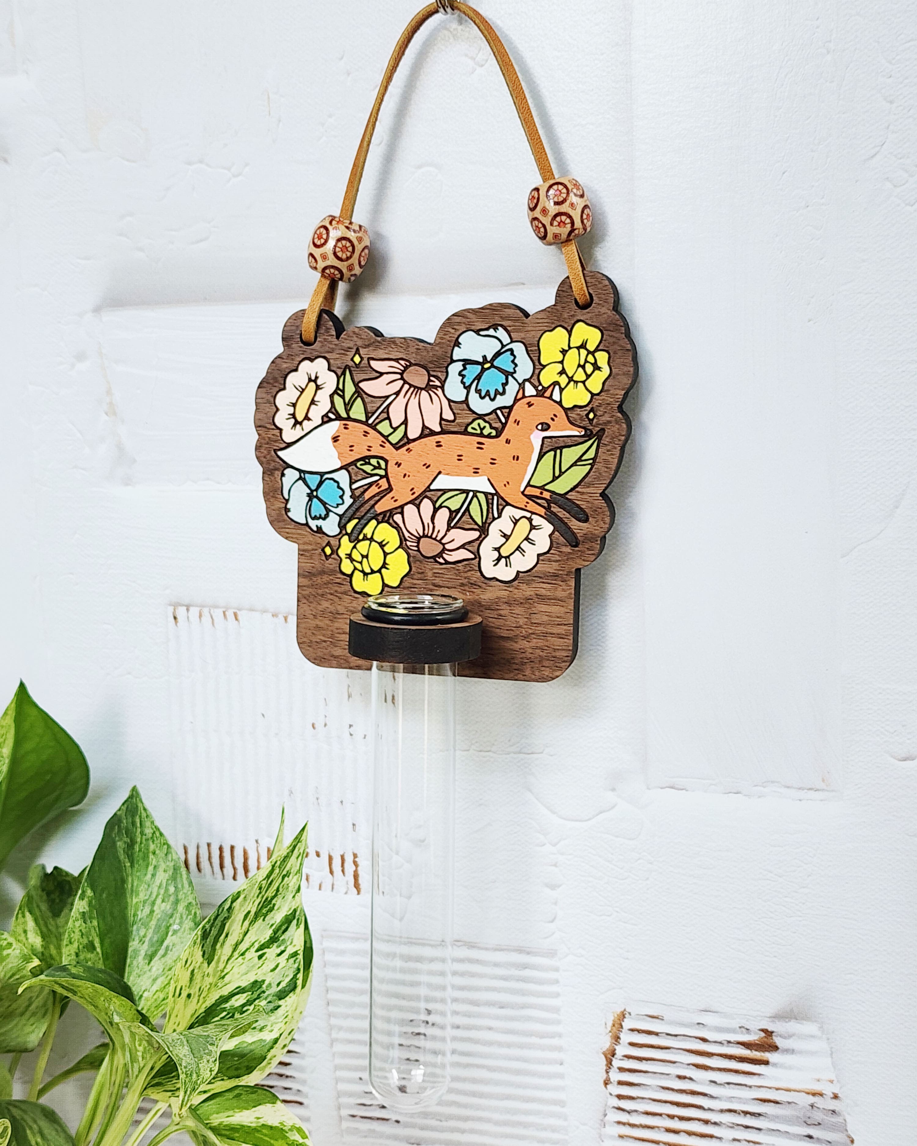 propagation station with a fox and flowers painted on it hanging on a white wall