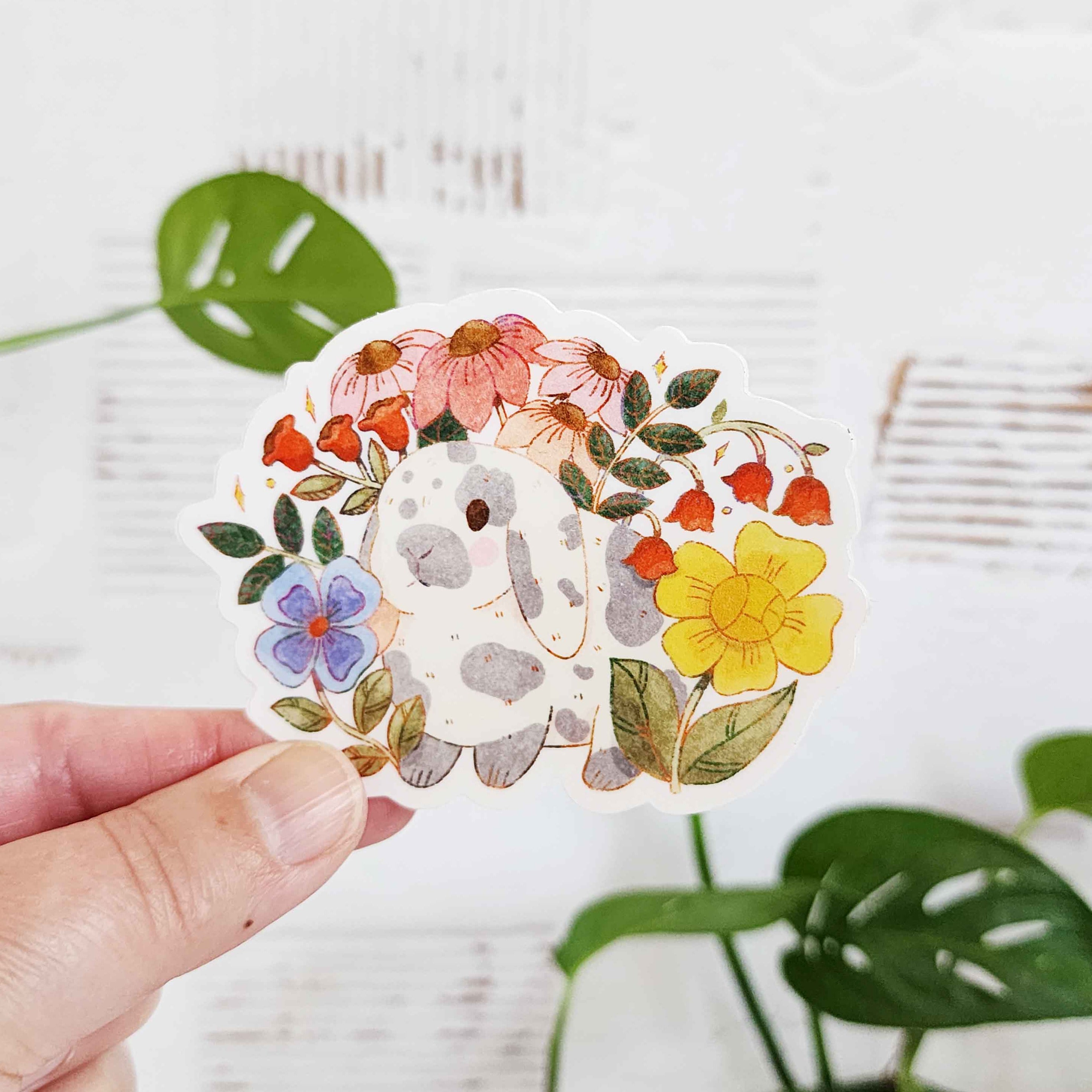 sticker of a gray and white rabbit in a garden of flowers