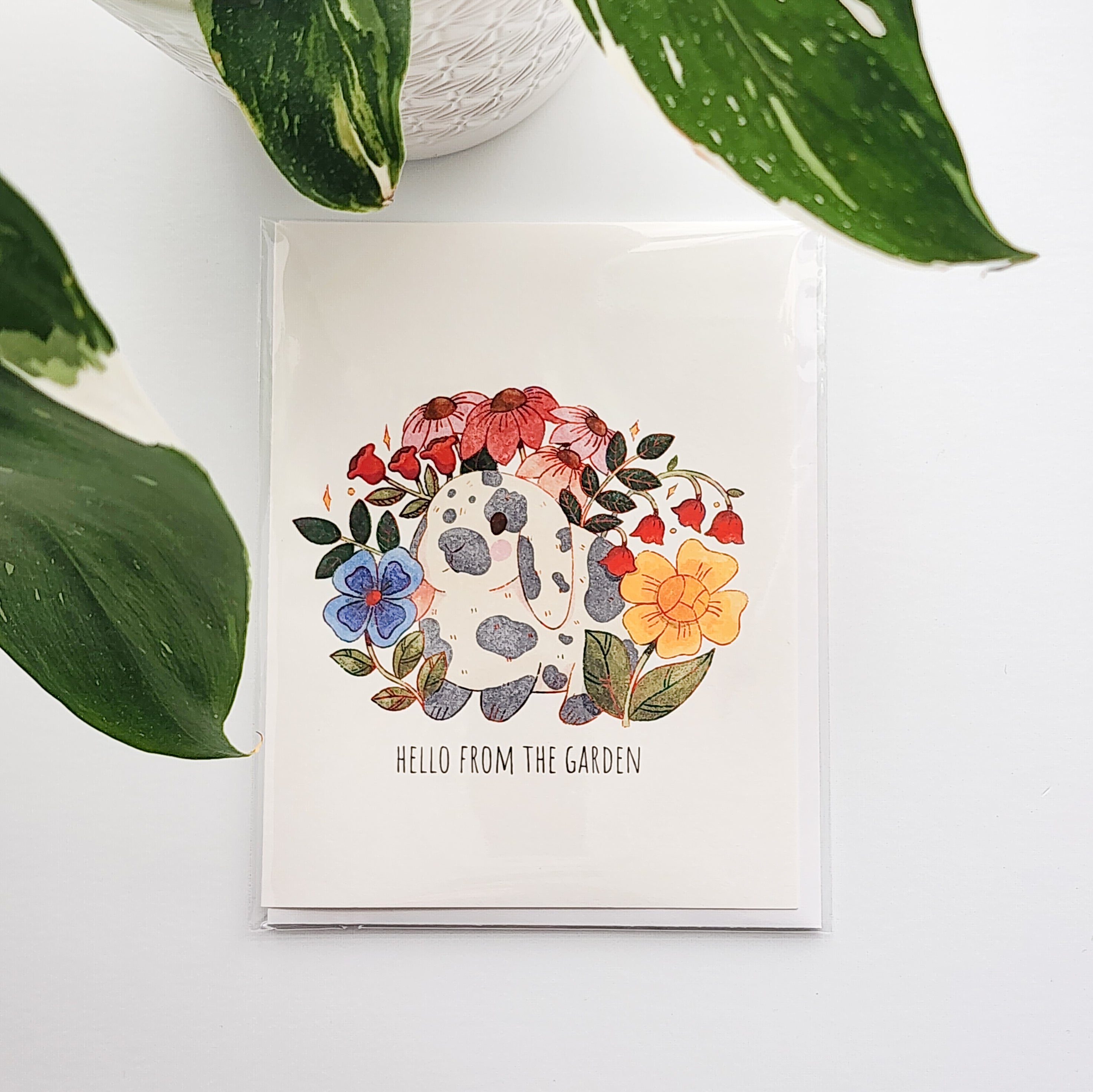 Card with a rabbit illustration surrounded by flowers and leaves on a white background.