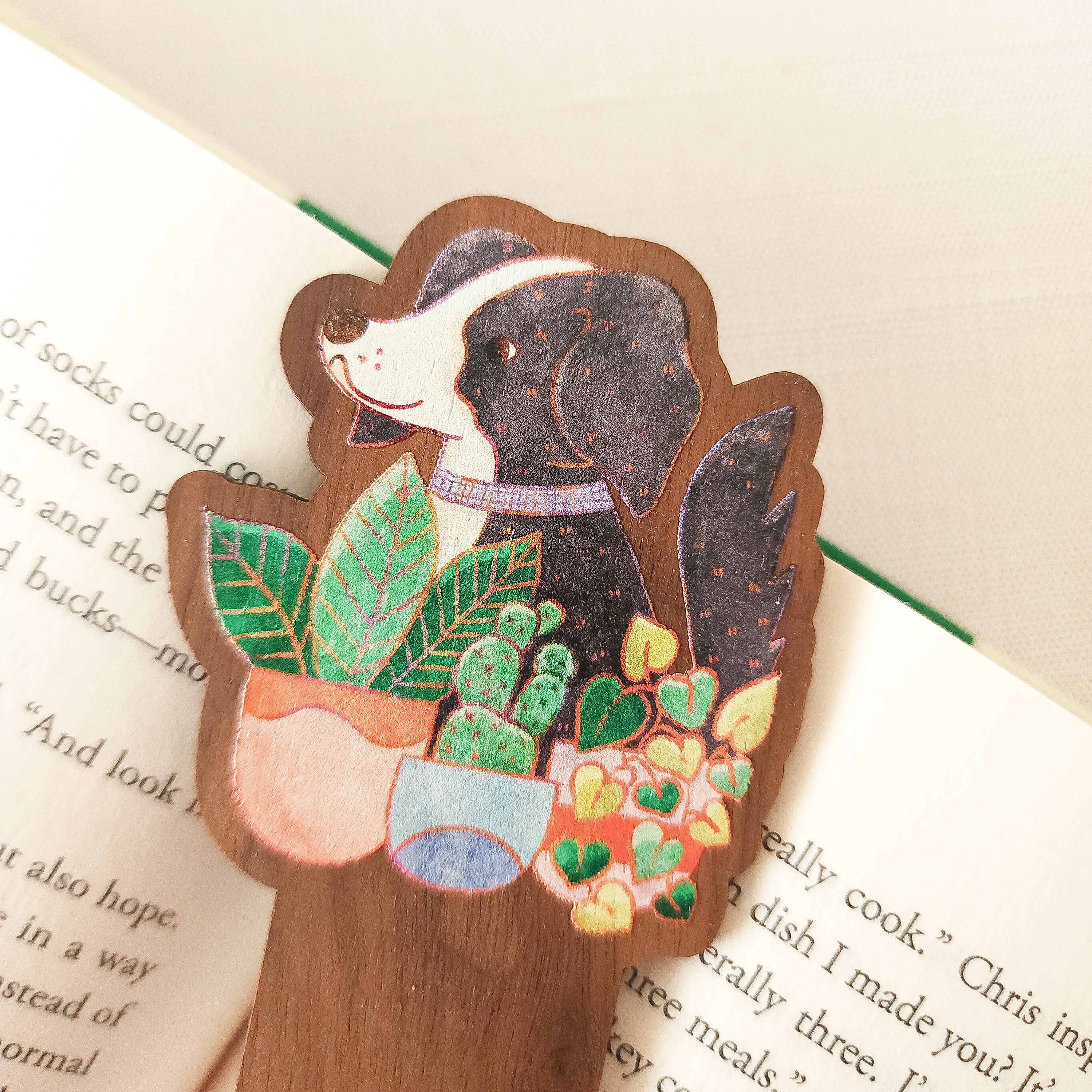wooden bookmark with an illustration of a dog and plants sitting on an open book