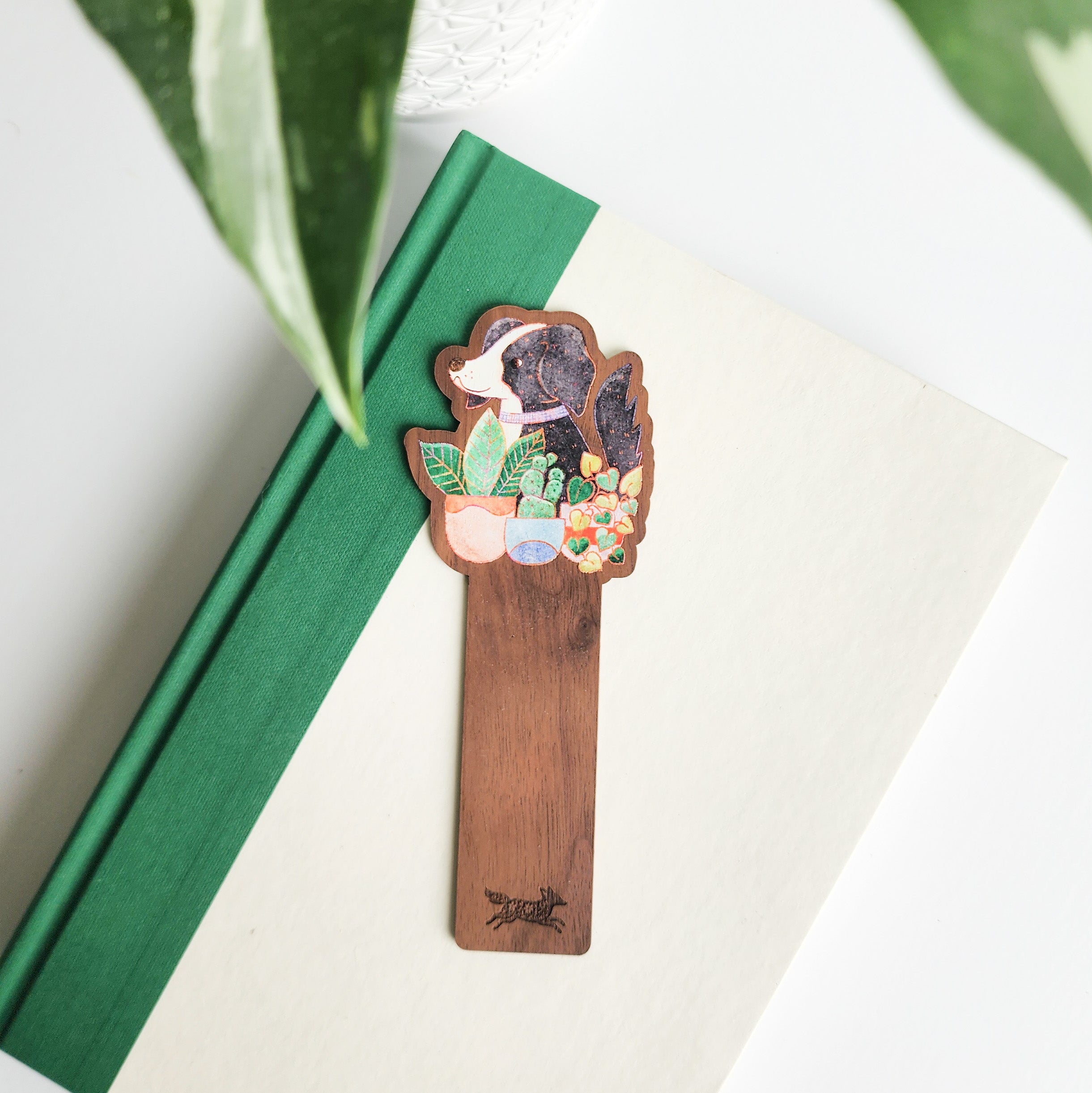 dog and houseplants bookmark on a green and white book on a white background with leaves