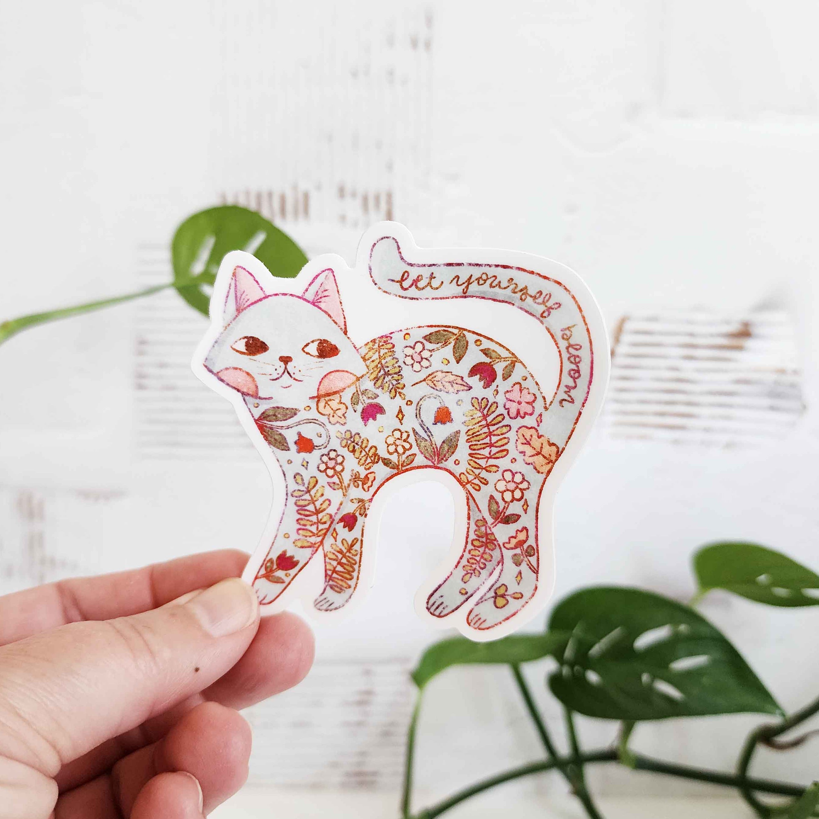 sticker of a cat filled with flowers and the words let yourself bloom