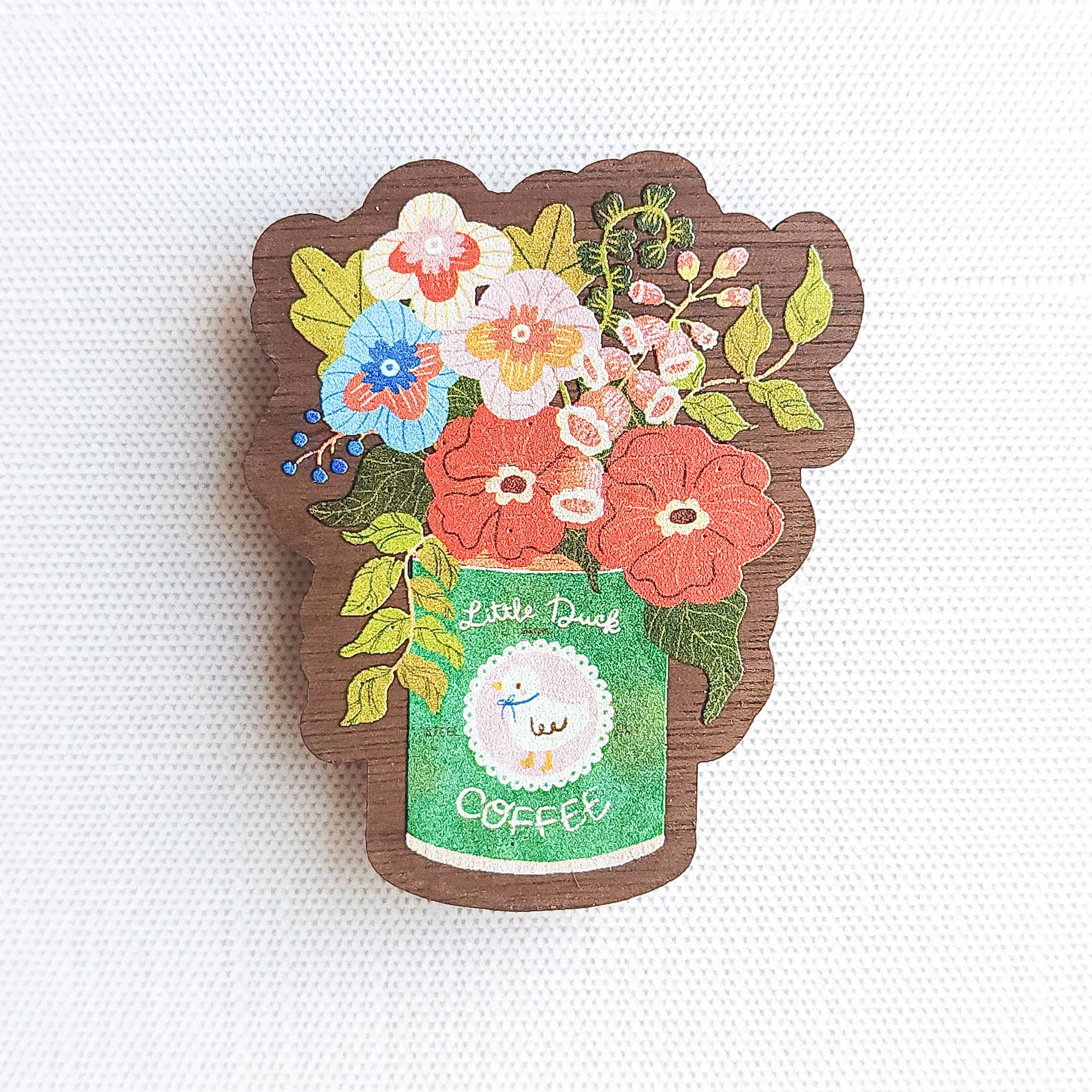 Wooden magnet with an illustrated Little Duck Coffee can repurposed as a vase, filled with cheerful pink, yellow, and blue flowers on a neutral background