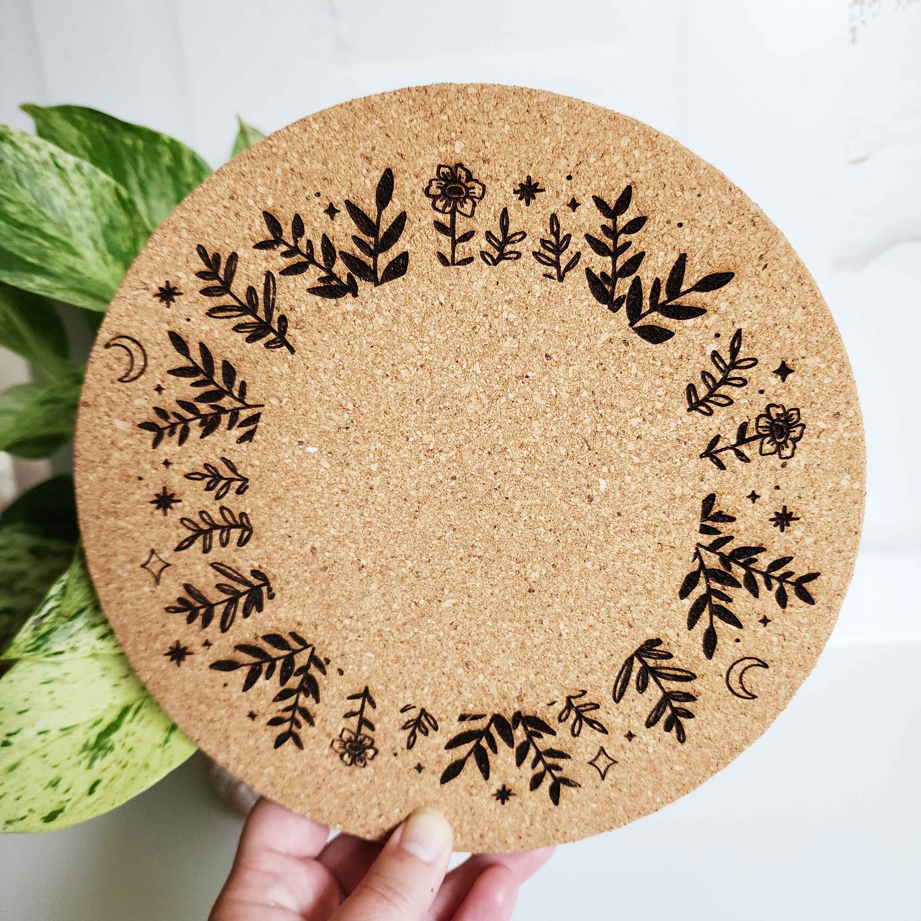 plant trivet with plants, stars and moons engraved in a circular pattern on it