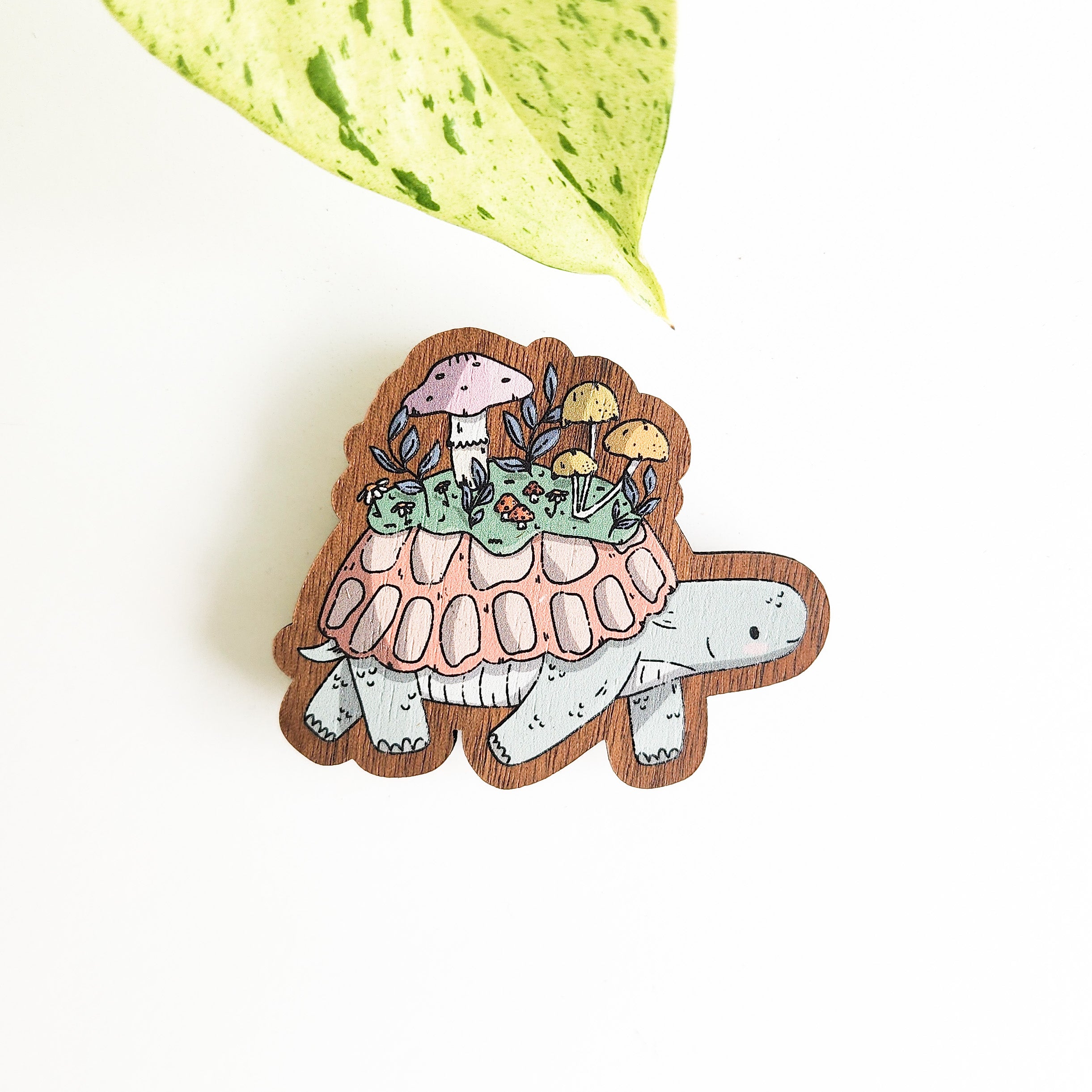Decorative turtle magnet with a mushroom and leaf design on a white background