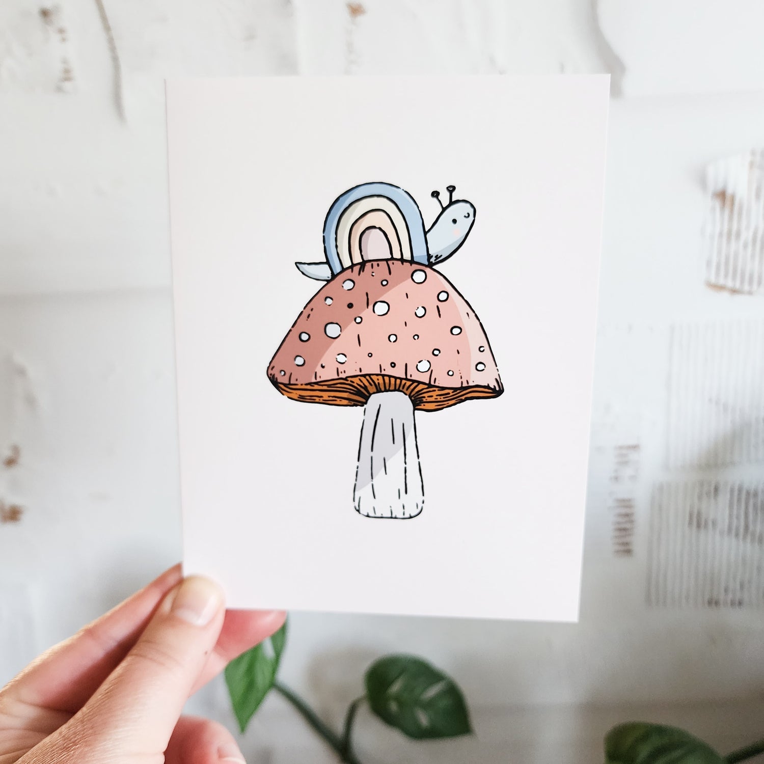 rainbow snail greeting card held in a hand