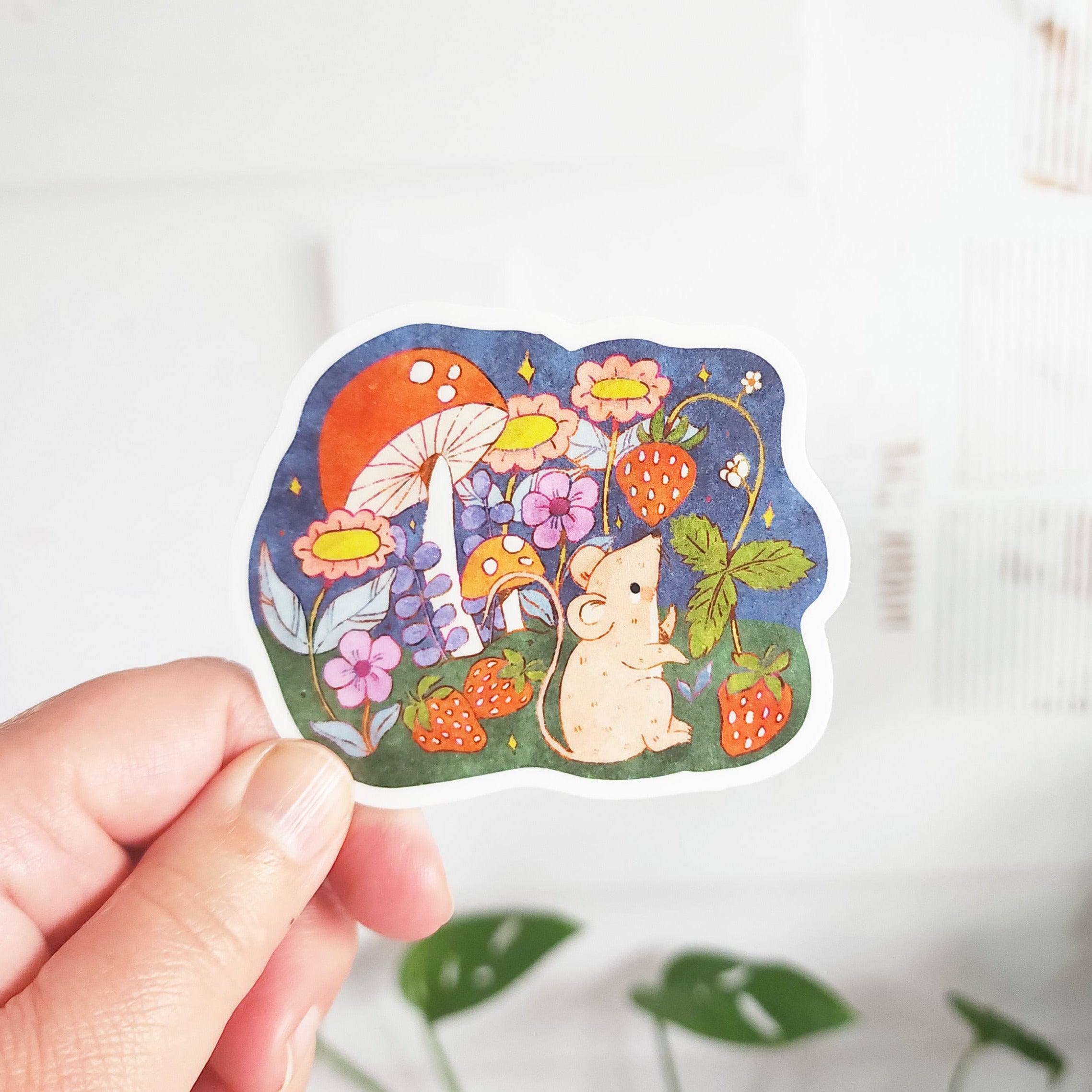 a hand holding a sticker with a mouse picking strawberries