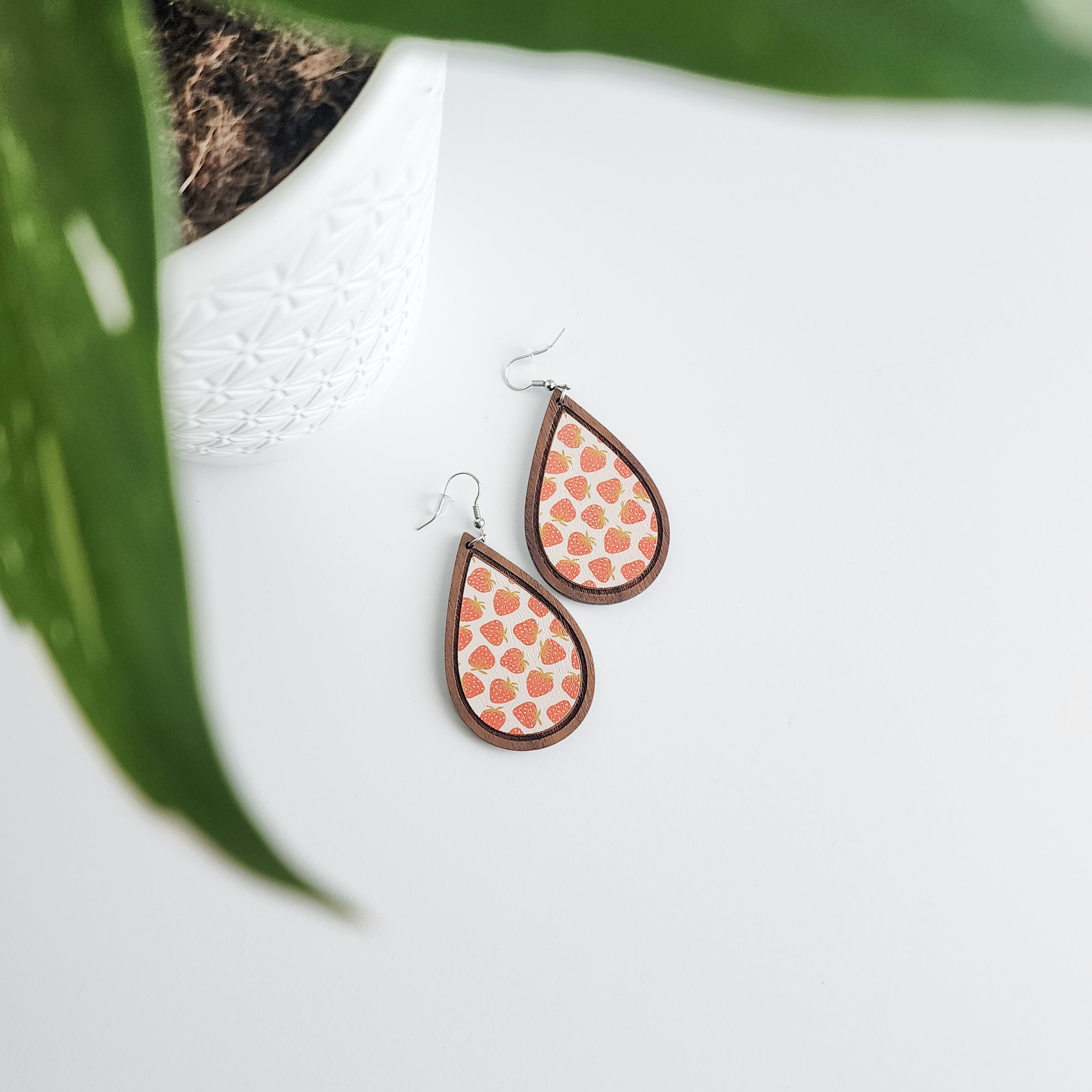 strawberry earrings on a white background with a potted plant