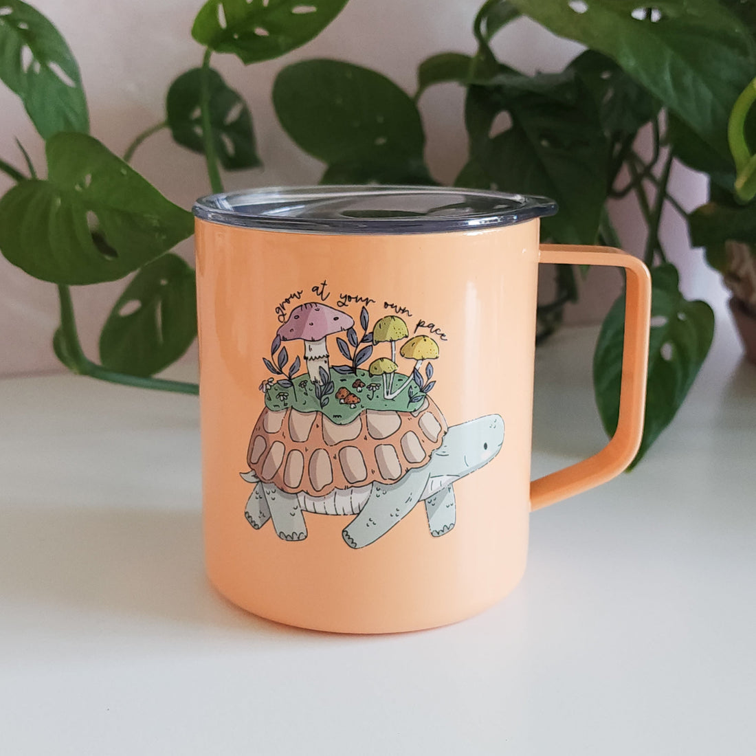orange turtle mug in front of a plant