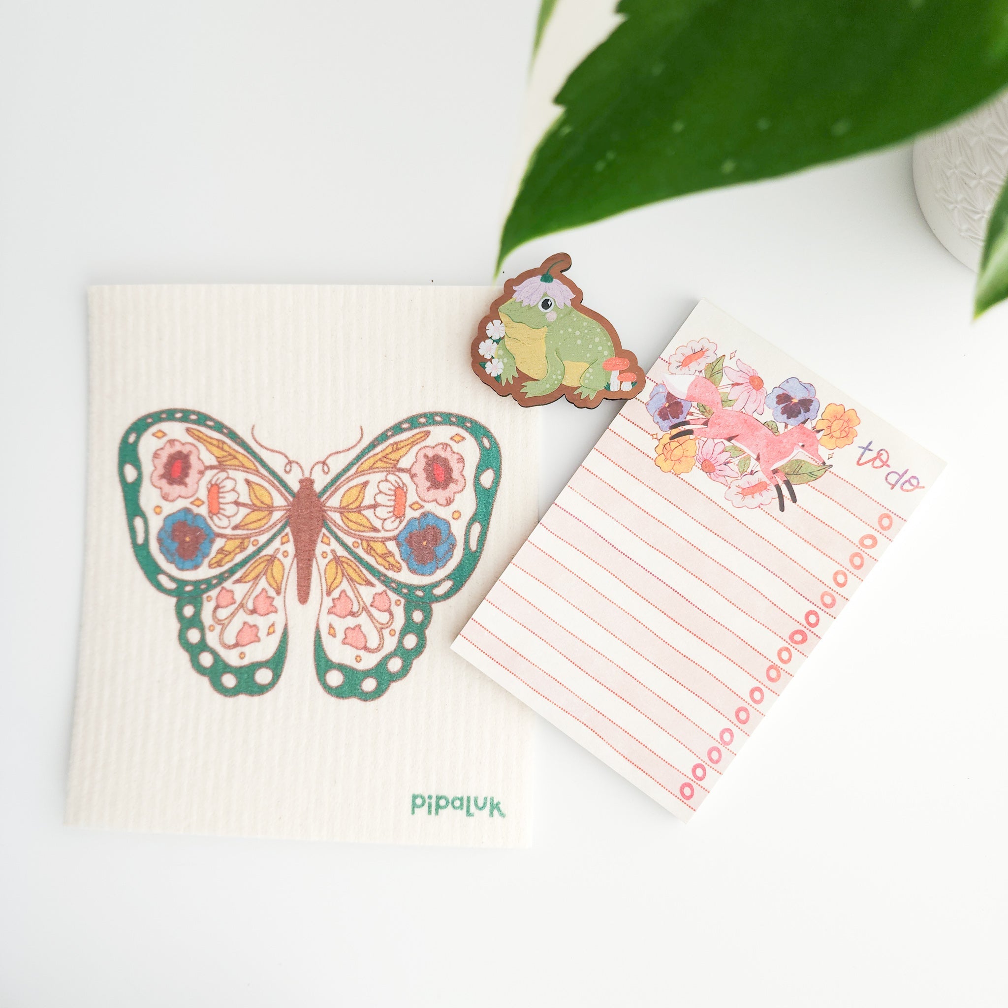butterfly dishcloth, fox notepad and frog magnet on a white background with a leaf