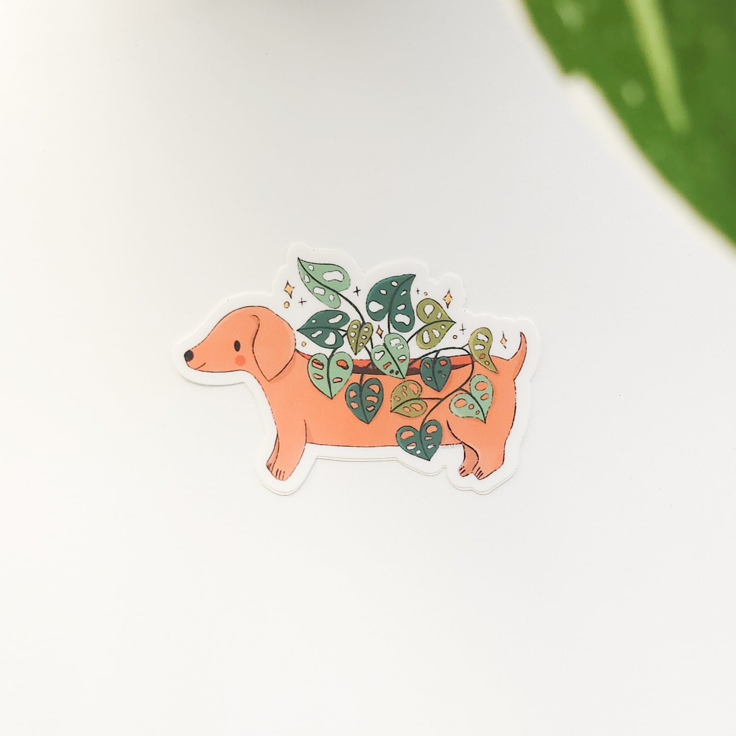 illustrated sticker of a dachshund planter on a white background with a leaf
