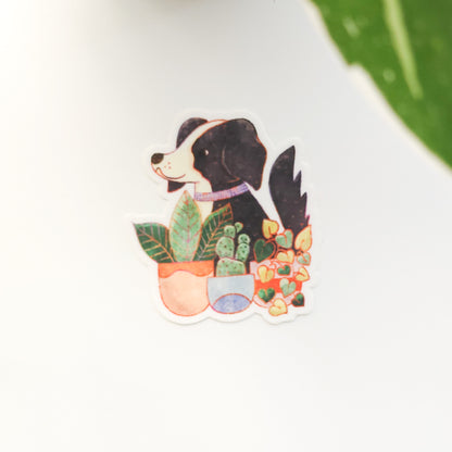 sticker of a black and white dog sitting in front of potted plants on a white background