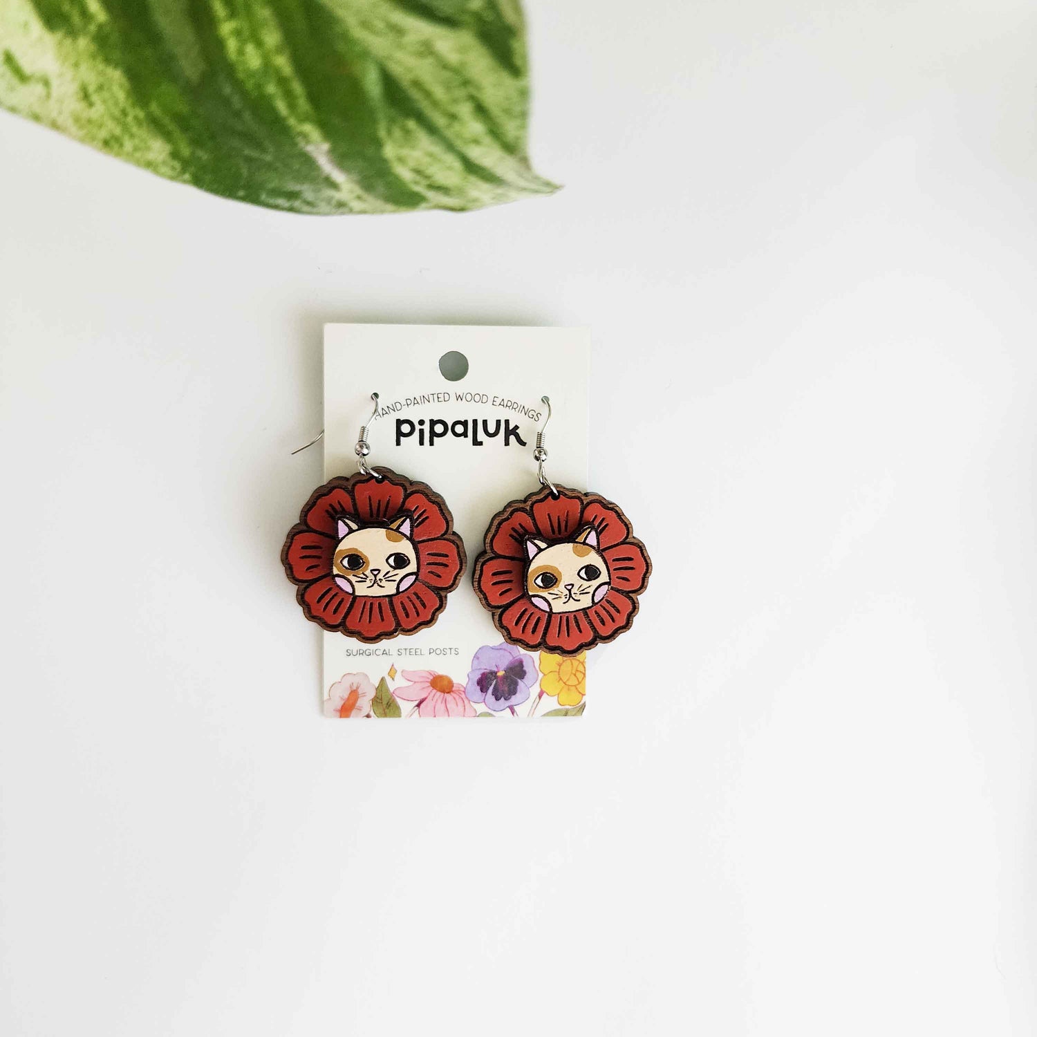 red flower earrings with a cat face in the center