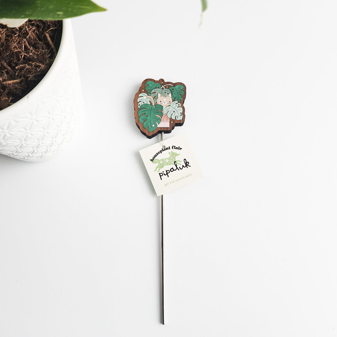 Wooden cat plant pick with a pipaluk label on a white background
