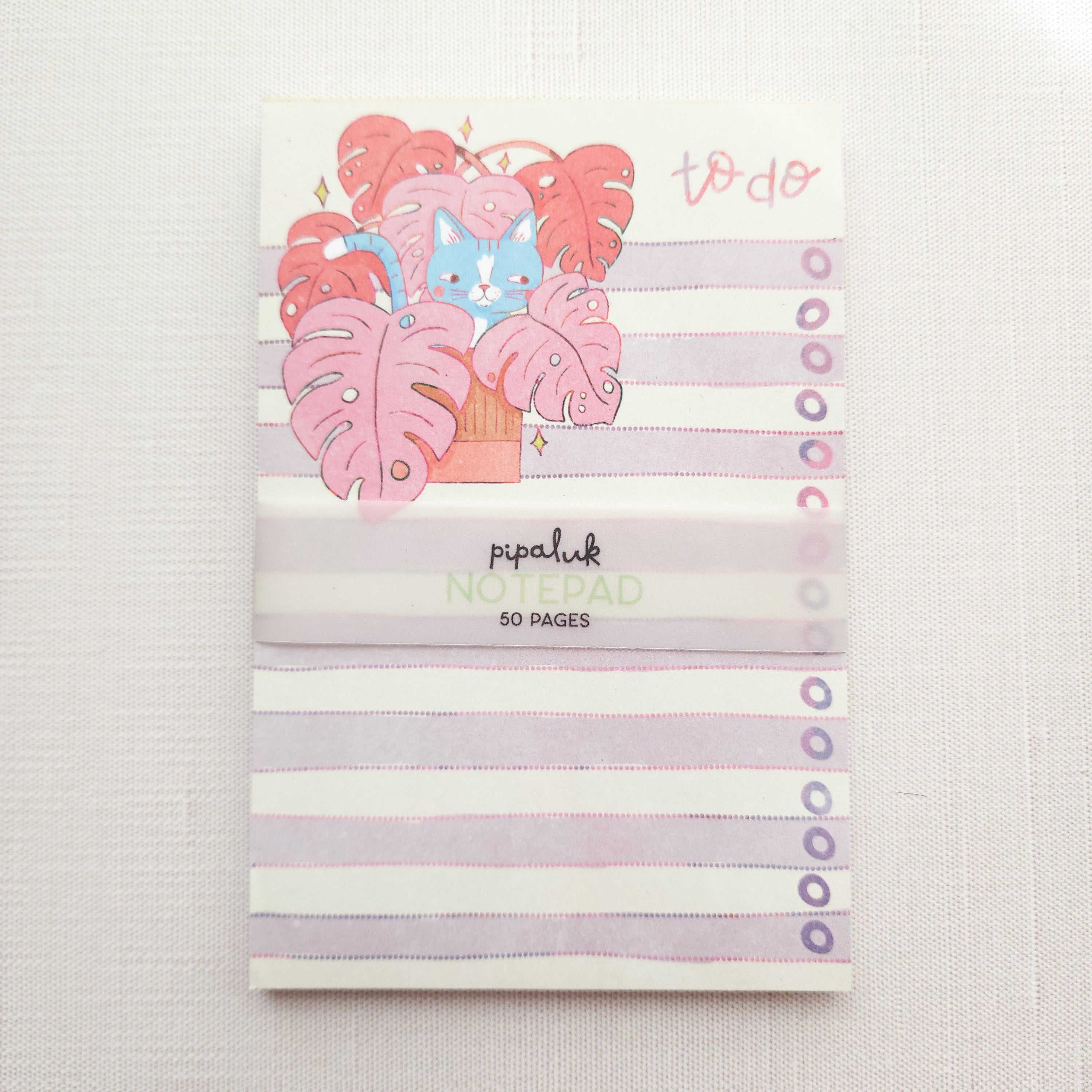 notepad with purple and white stripes and an illustration of a cat in a monstera plant and the words to do