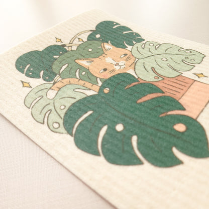 close up image of a swedish dishcloth with an illustration of a cat in a monstera plant, to show the texture