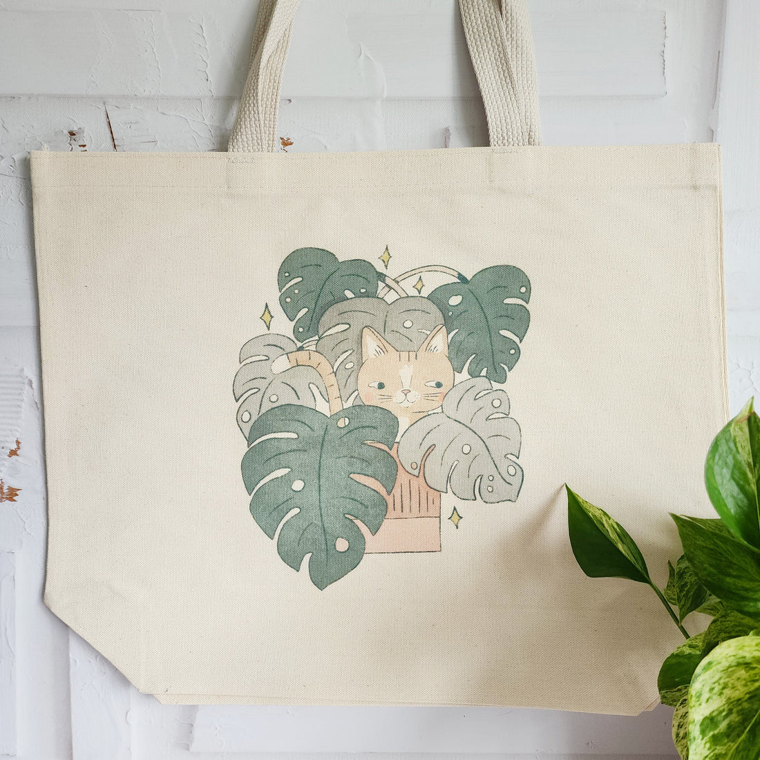 tote bag with a cat in a monstera plant hanging on a wall