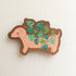 wooden magnet with an illustration of a dachshund planter with a cheese plant on a linen background