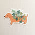 sticker with an illustration of a dachshund planter with a cheese plant on a linen background