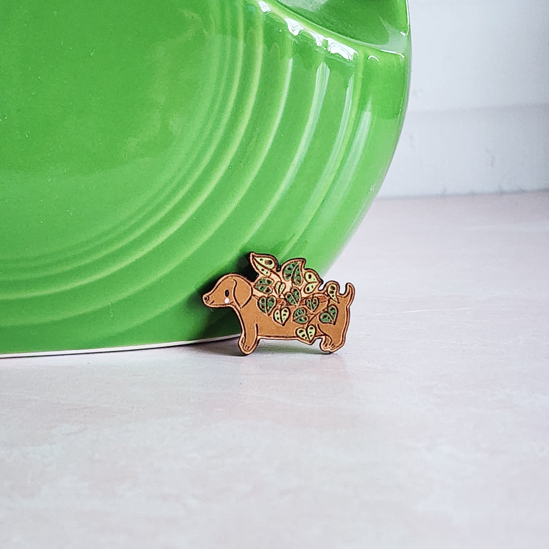 brown dachshund planter pin with leaves in front of a green vase