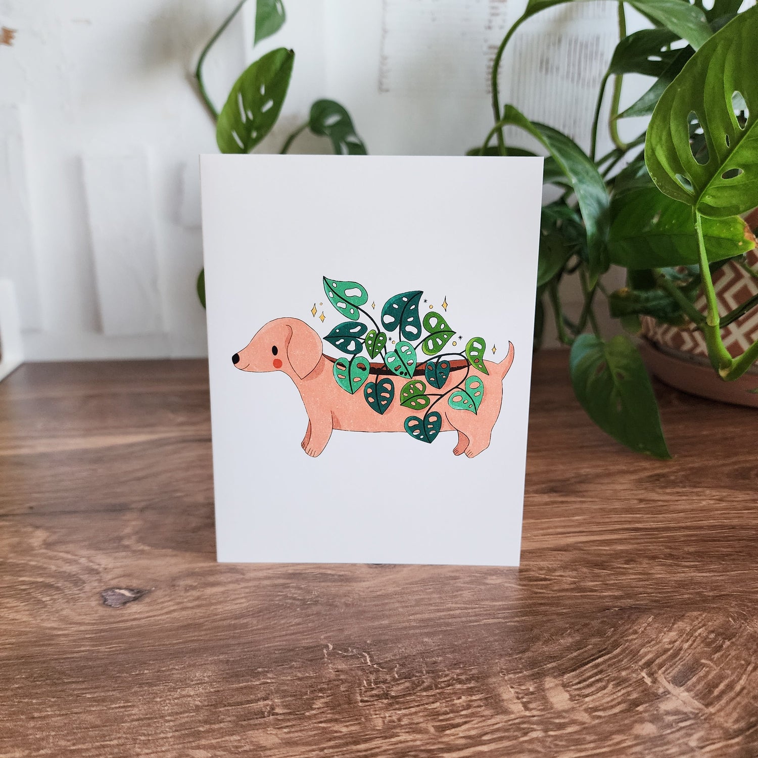 dachshund planter greeting card sitting in front of a plant