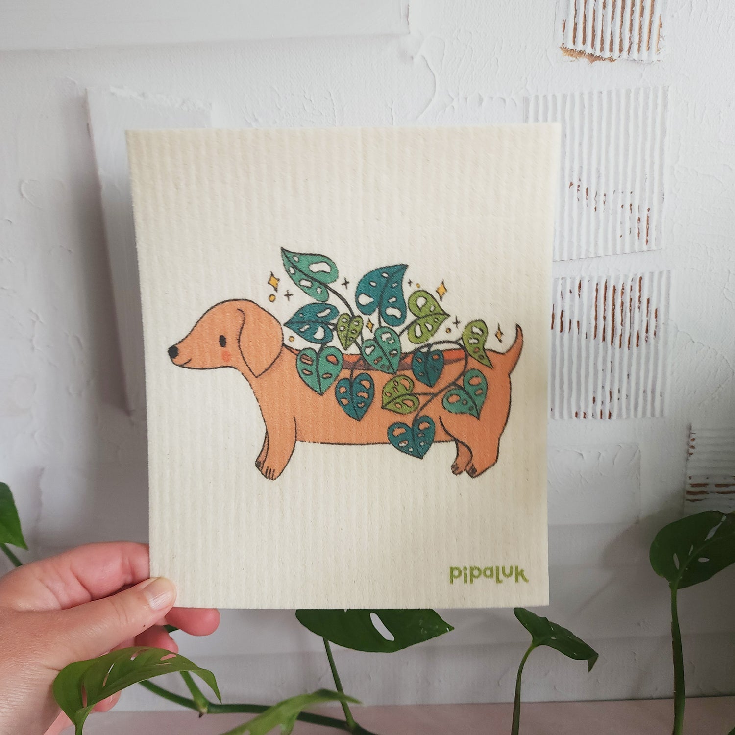 dachshund planter dishcloth held in a hand against a white background