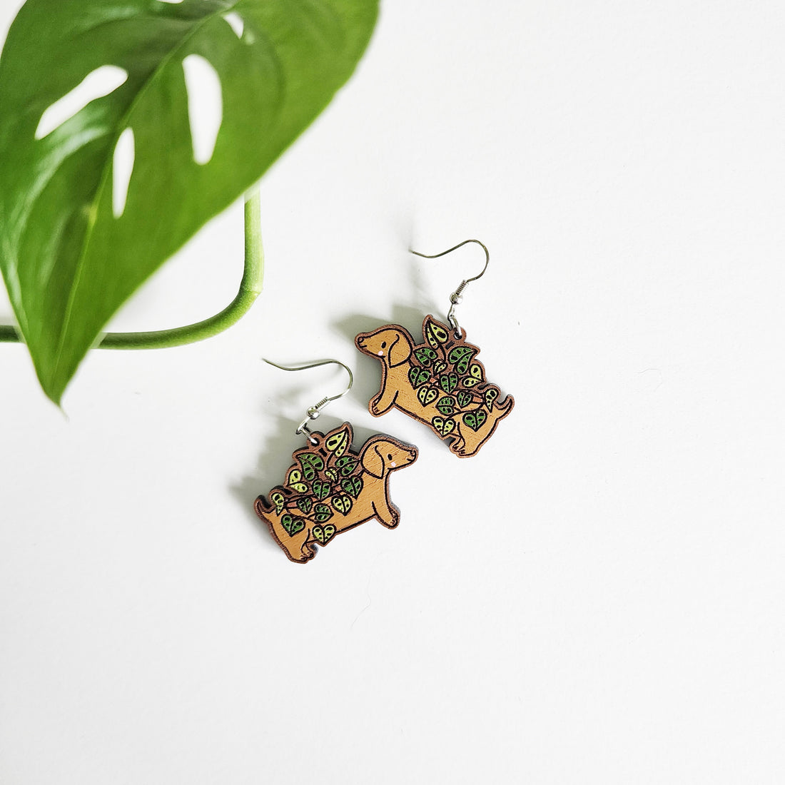 dachshund planter earrings on a white background with a green leaf