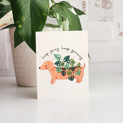 Card with a dachshund growing plants and text &