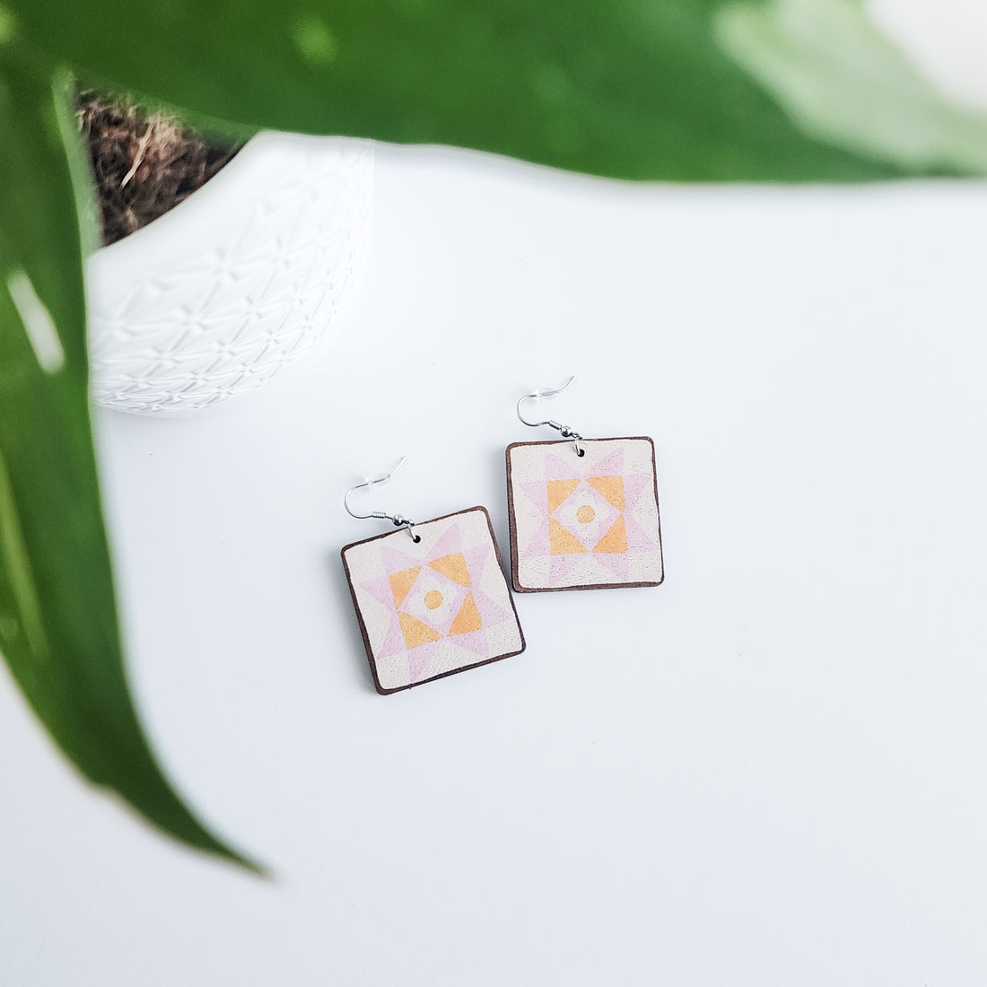 daisy star earrings on a white background with a potted plant