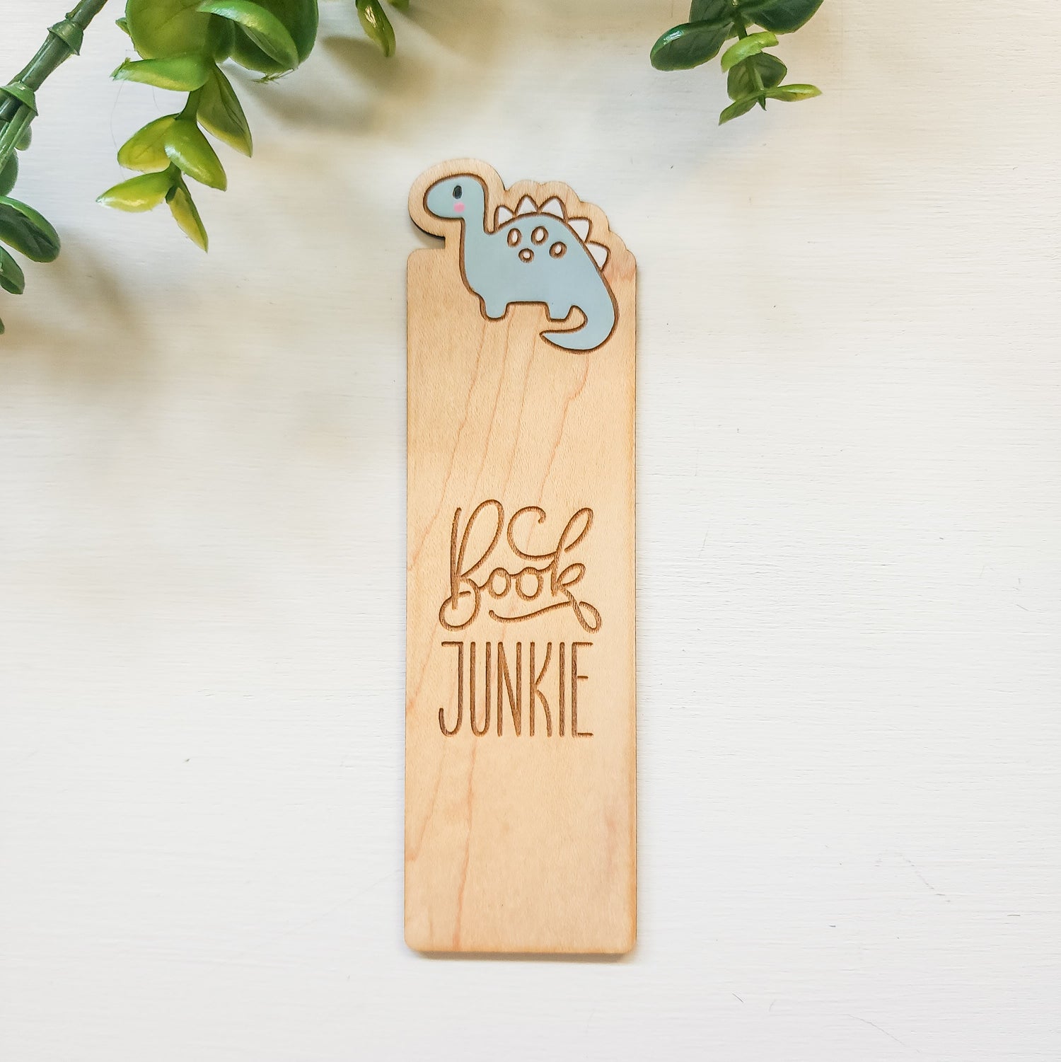 engraved wooden bookmark with a painted dinosaur and the words book junkie