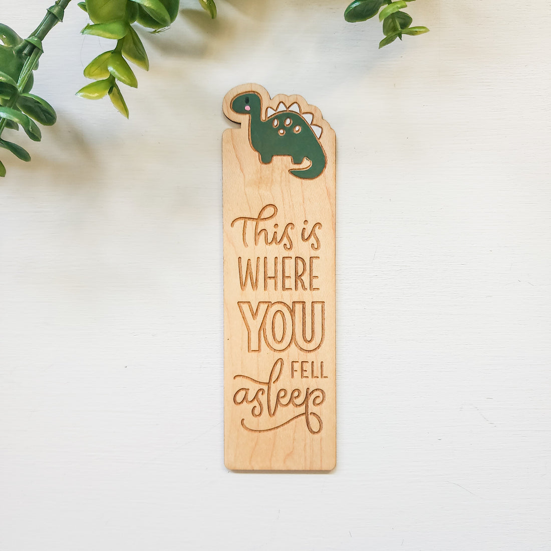 wooden bookmark with a painted dinosaur and the words this is where you fell asleep engraved