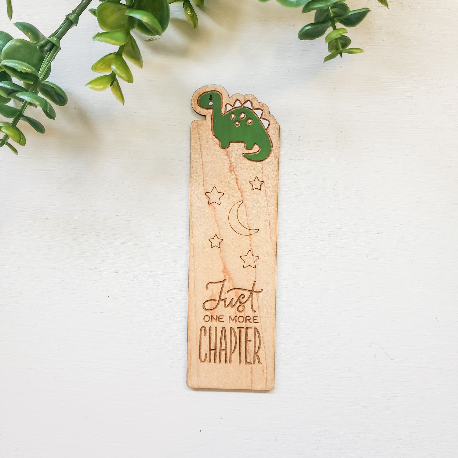wooden bookmark engraved with a dinosaur and the words just one more chapter