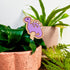 purple dinosaur plant pick insde a house plant