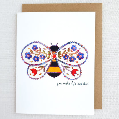 Greeting card with a colorful bee design and floral elements on a white background.