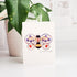 Card with a bee design with flowers on a white surface with a plant in the background