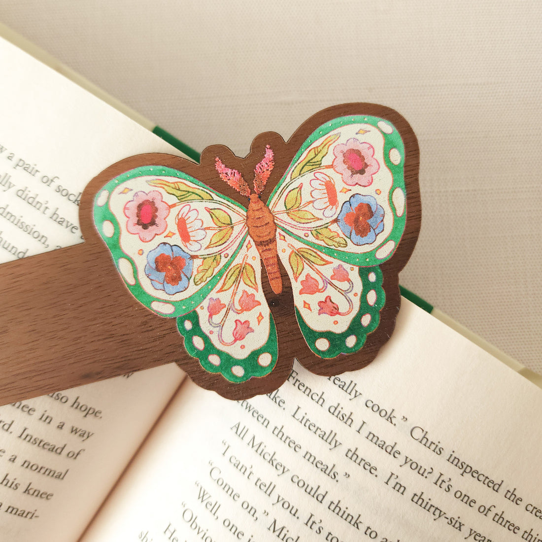 wooden bookmark with an illustration of a butterfly with flowers in its wings on an open book