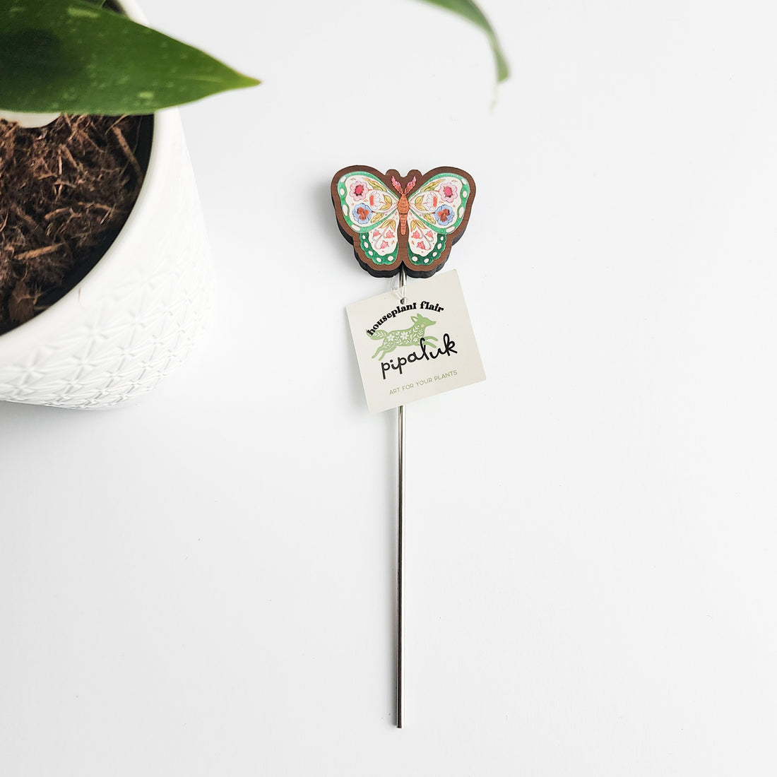 Butterfly-shaped plant stake with a pipaluk tag on a white background